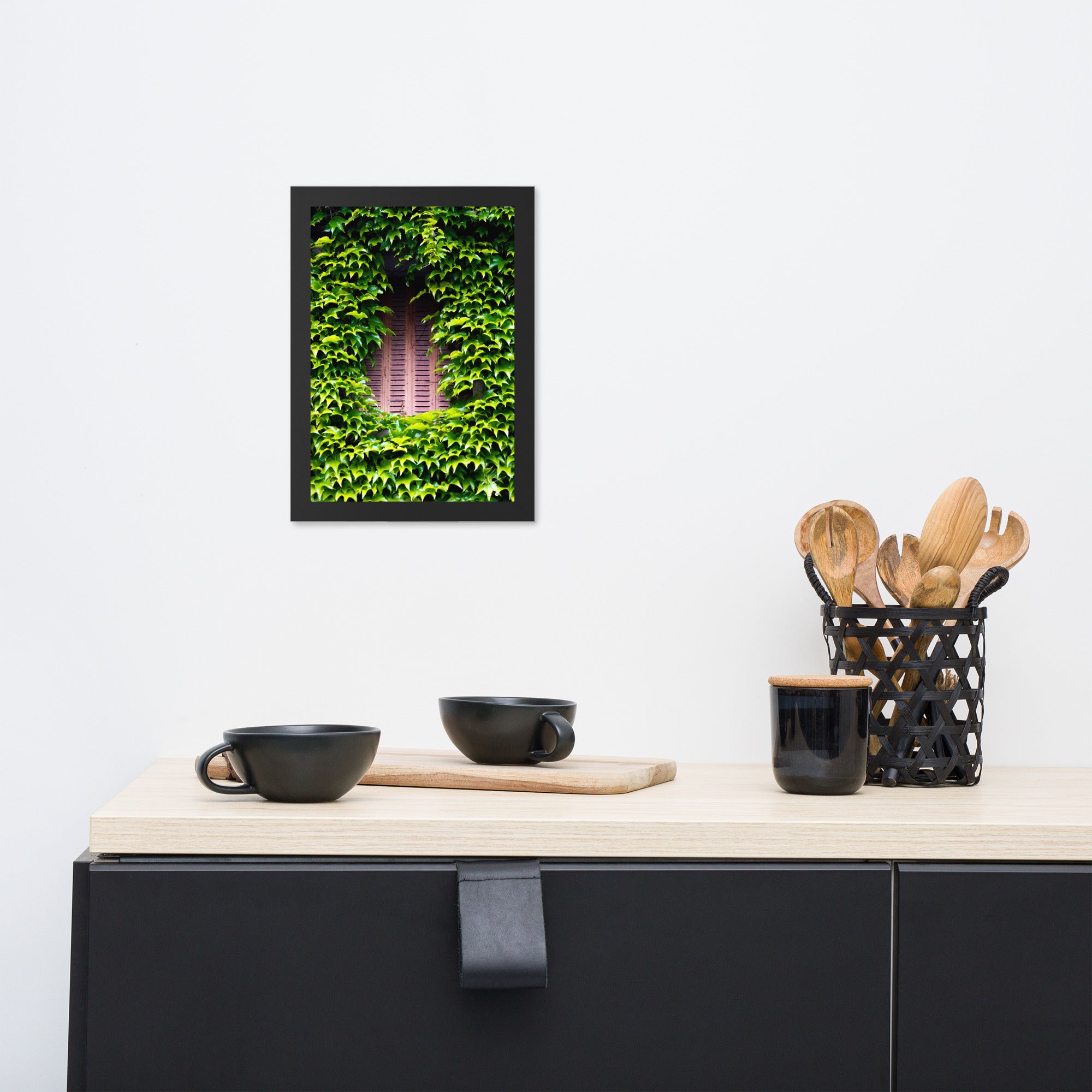 Photographie montrant une vieille fenêtre aux volets rouges, enveloppée par des plantes vertes grimpantes. Une représentation poétique de l'interaction entre nature et histoire.