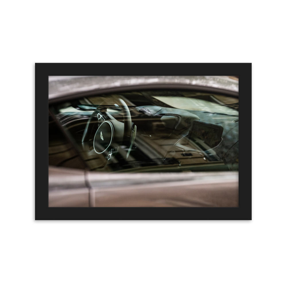 Photographie de l'intérieur d'une Aston Martin Vantage, mettant en valeur le tableau de bord en cuir et le volant.