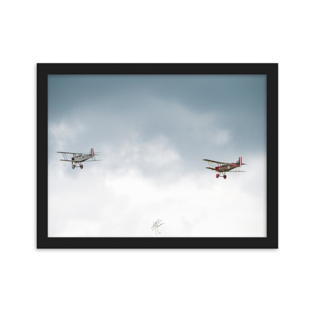 Deux avions de combat de la Première Guerre Mondiale s'élevant contre un ciel gris-blanc, encapsulant l'héroïsme de l'époque. Poster encadré de haute qualité signé 'Tagazou'.