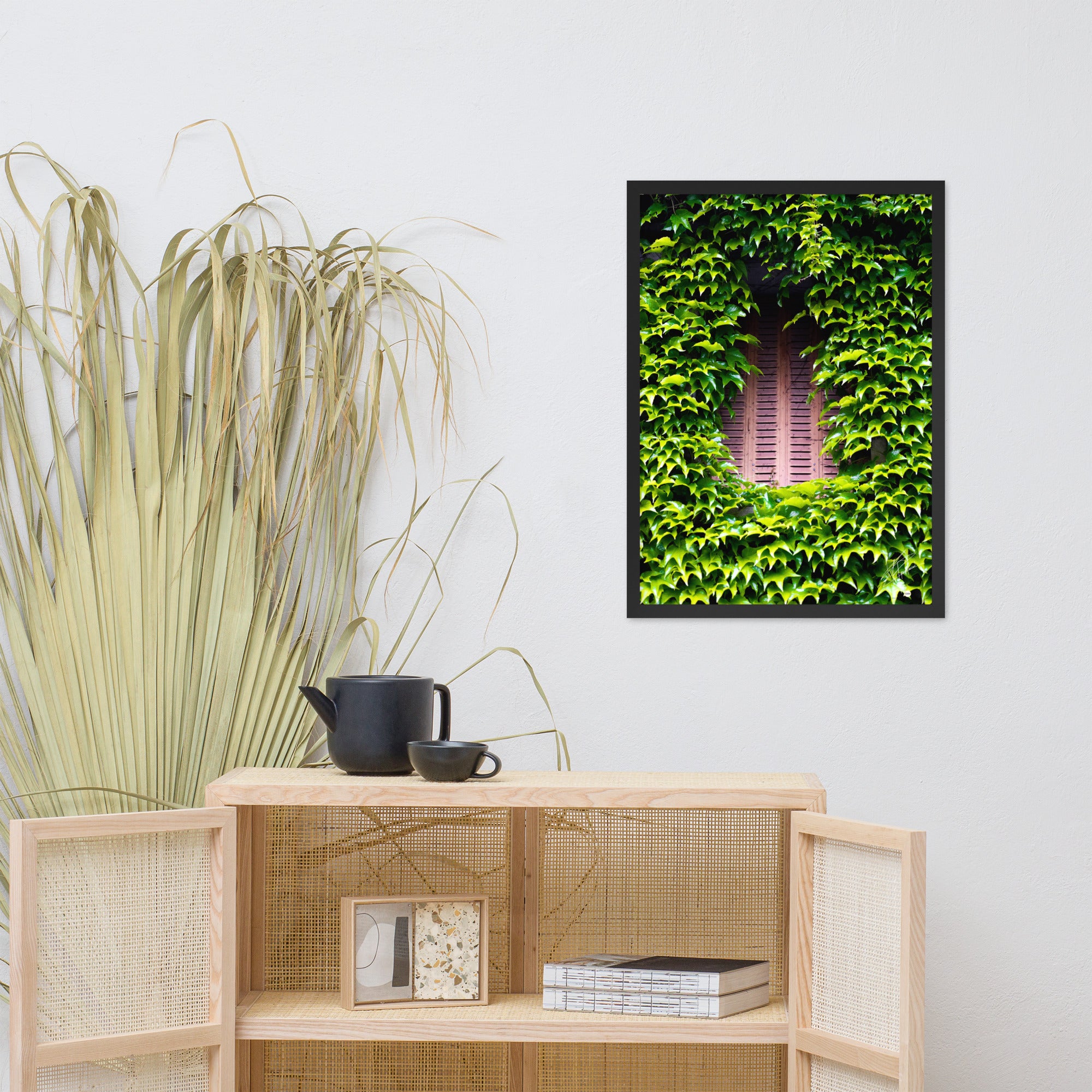 Photographie montrant une vieille fenêtre aux volets rouges, enveloppée par des plantes vertes grimpantes. Une représentation poétique de l'interaction entre nature et histoire.