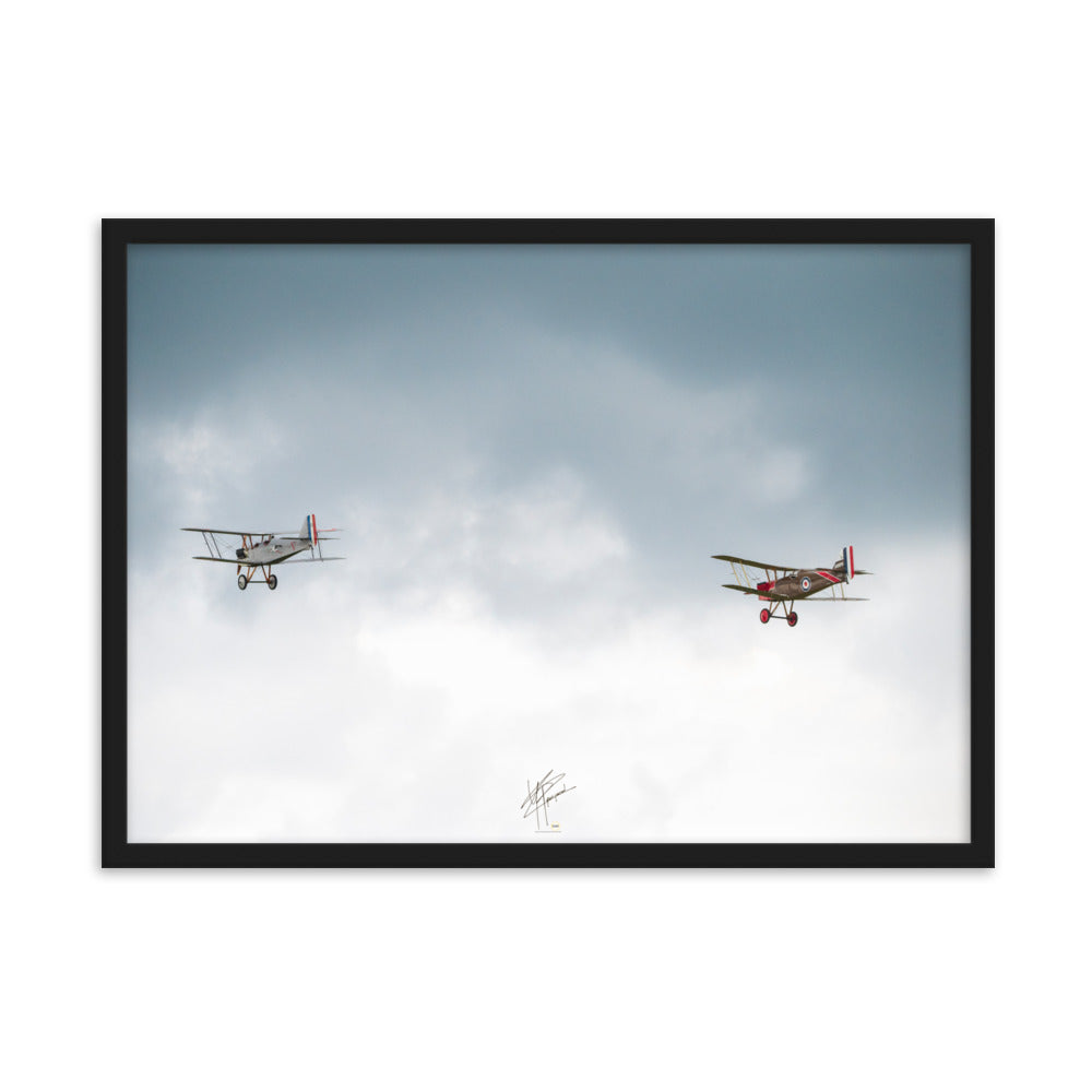 Deux avions de combat de la Première Guerre Mondiale s'élevant contre un ciel gris-blanc, encapsulant l'héroïsme de l'époque. Poster encadré de haute qualité signé 'Tagazou'.