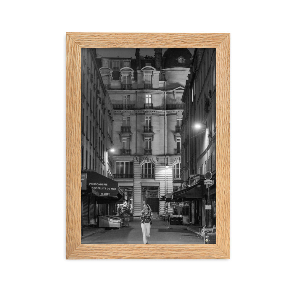 Photographie en noir et blanc d'une rue parisienne déserte la nuit, illuminée par les lumières douces des lampadaires, évoquant une atmosphère mystérieuse et mélancolique.