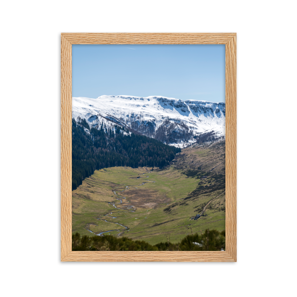 Poster d'une vallée verdoyante avec des montagnes enneigées en arrière-plan, situées dans le Cantal