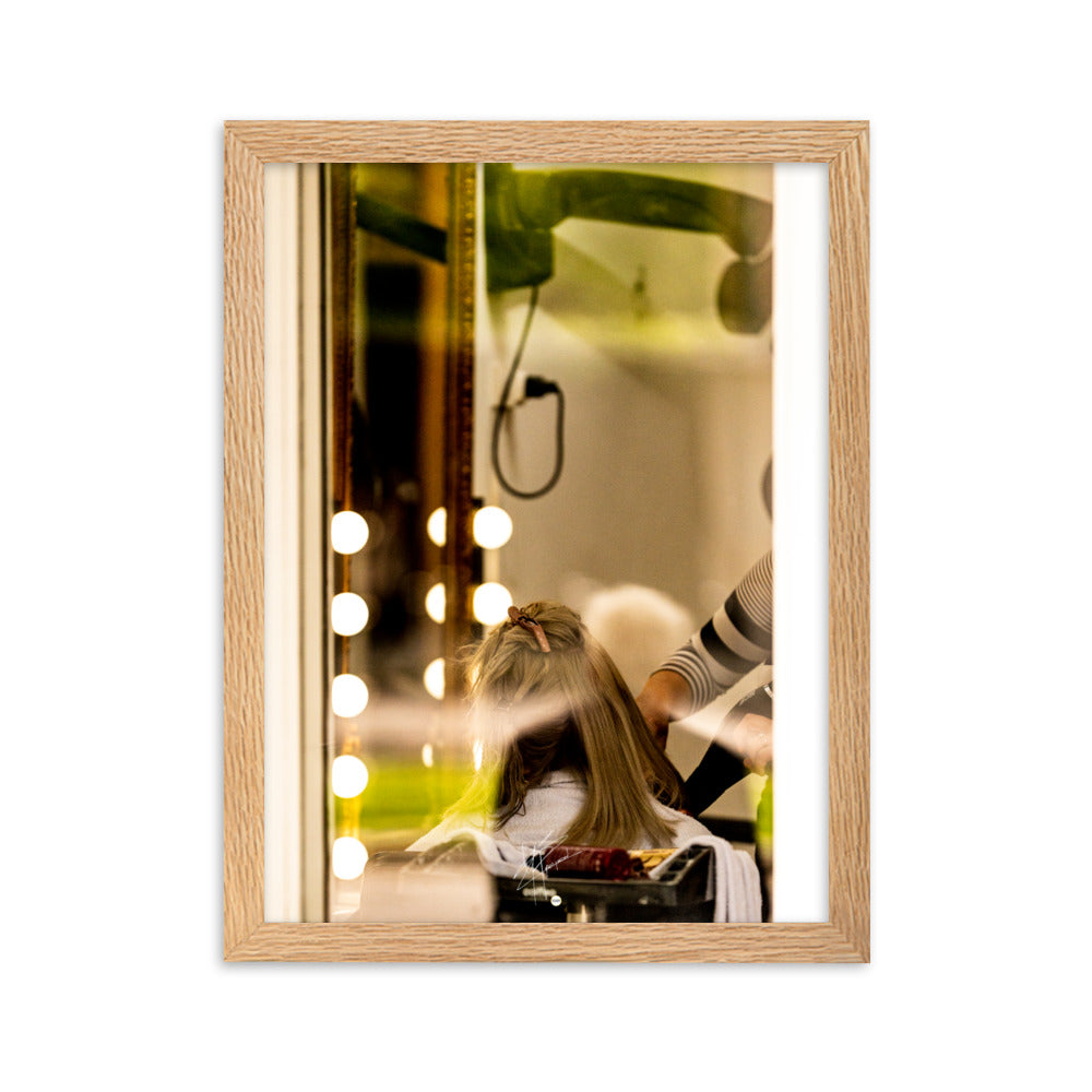 Photographie d'une scène à travers la vitre d'un salon de coiffure, révélant un moment ordinaire mais expressif d'une coiffeuse en plein travail.