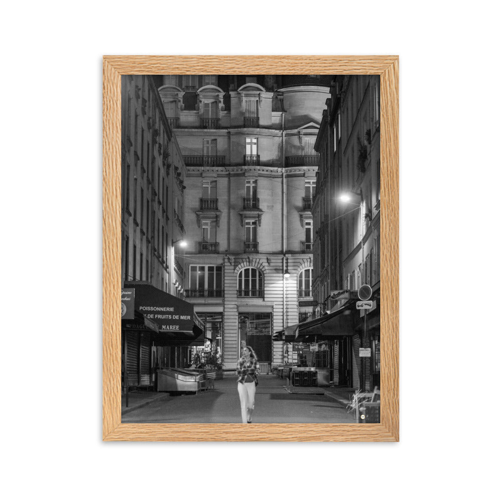 Photographie en noir et blanc d'une rue parisienne déserte la nuit, illuminée par les lumières douces des lampadaires, évoquant une atmosphère mystérieuse et mélancolique.