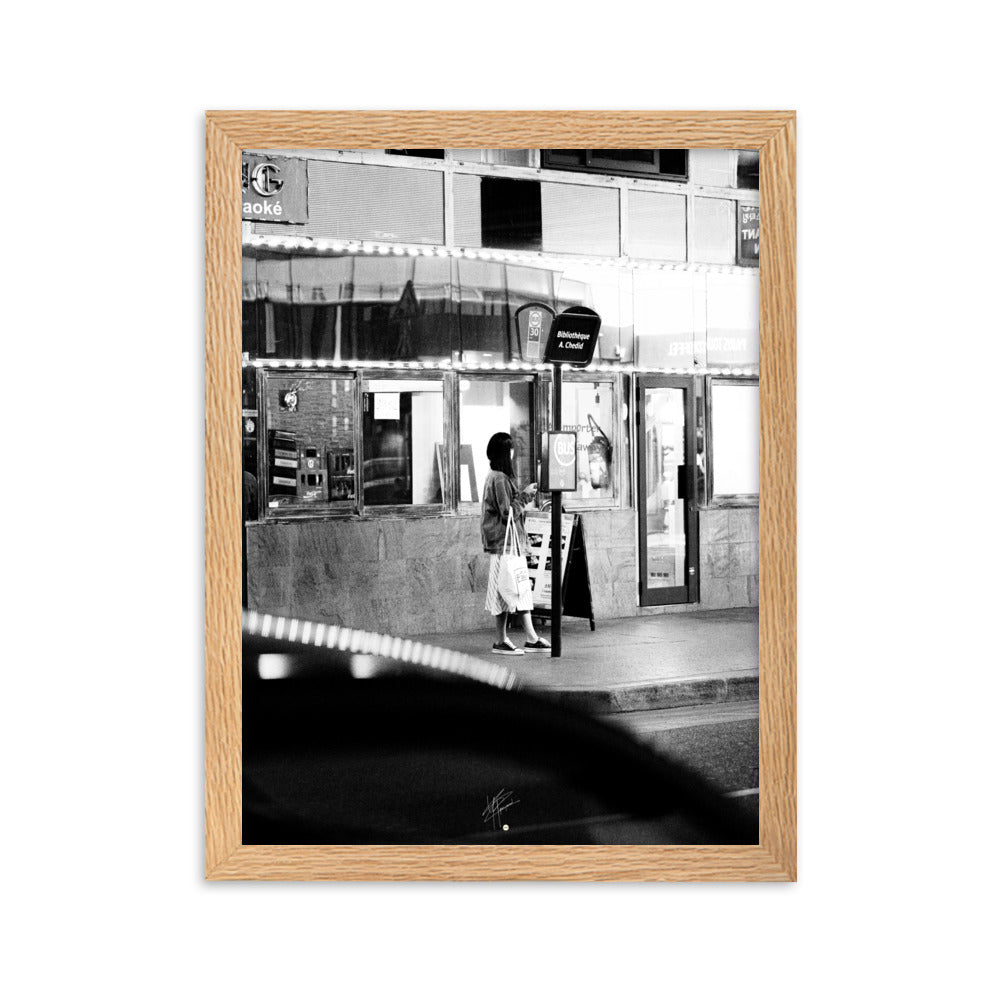 Photographie en noir et blanc d'une femme éclairée par son téléphone dans une rue sombre, mettant en évidence le contraste lumineux de la scène urbaine.