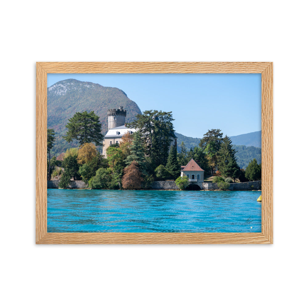 Vue panoramique du Château de Duingt, dominé par des montagnes, avec le Lac d'Annecy reflétant l'édifice, encadré en chêne.