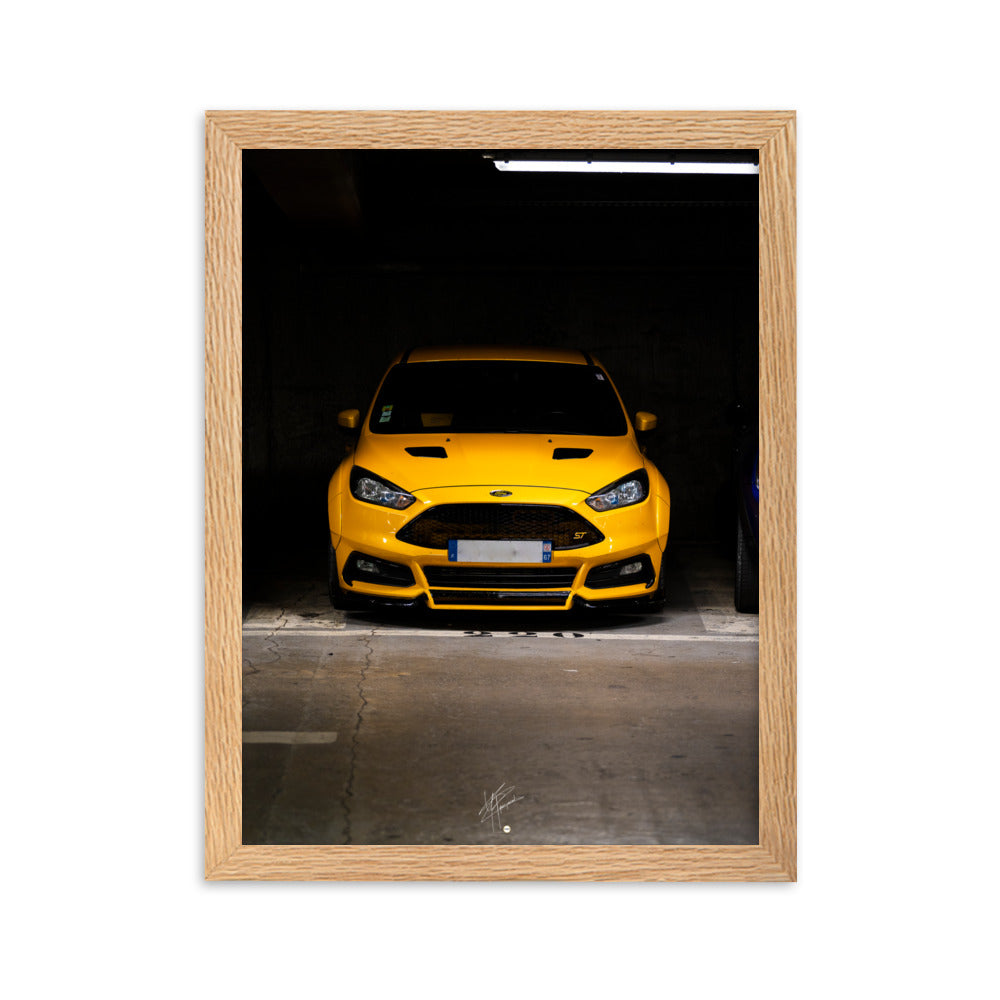 Vue frontale d'une Ford Focus ST en éclatant jaune, mise en lumière dans un parking souterrain avec un éclairage distinctif, encadrement en chêne.