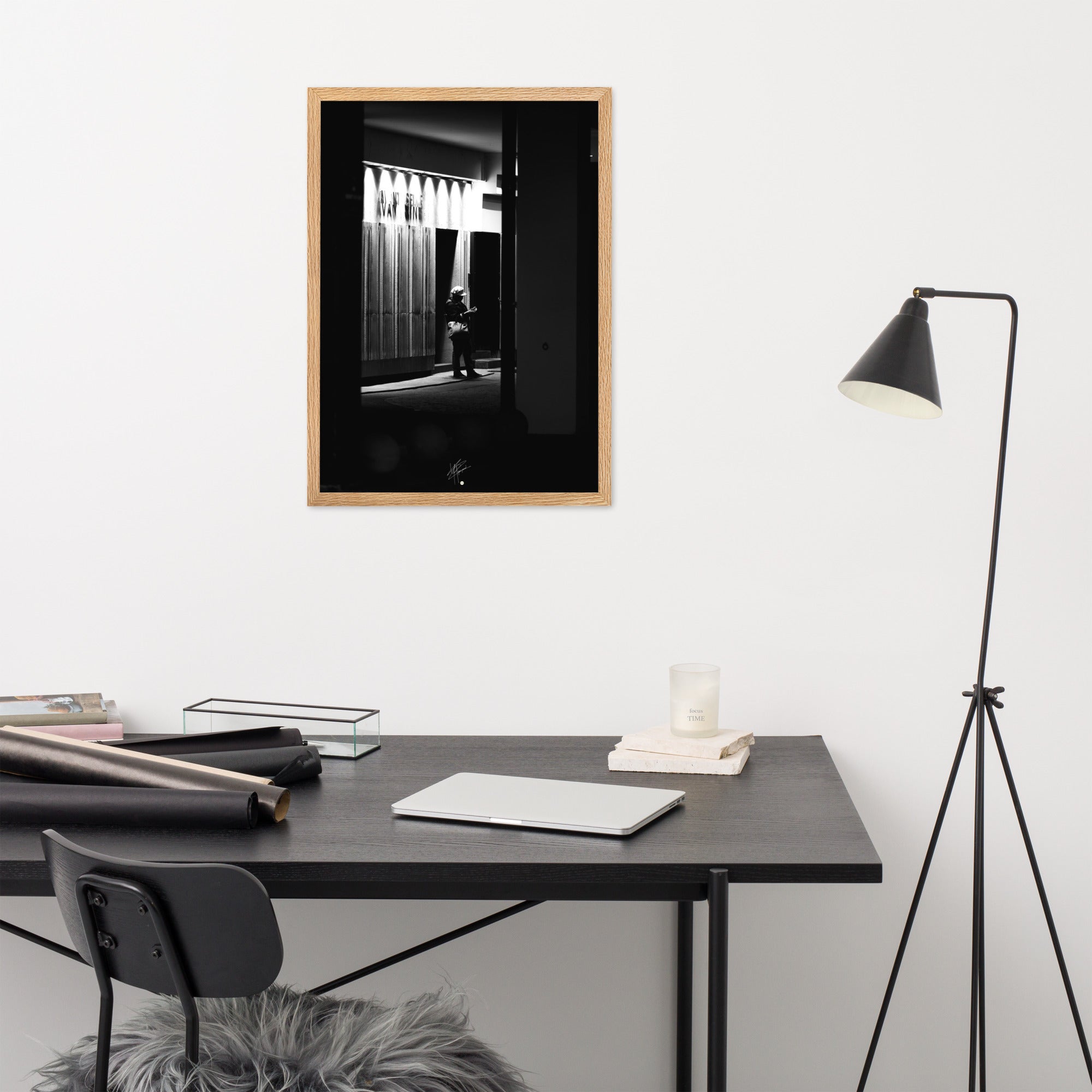 Photographie en noir et blanc d'une femme éclairée par son téléphone dans une rue sombre, mettant en évidence le contraste lumineux de la scène urbaine.