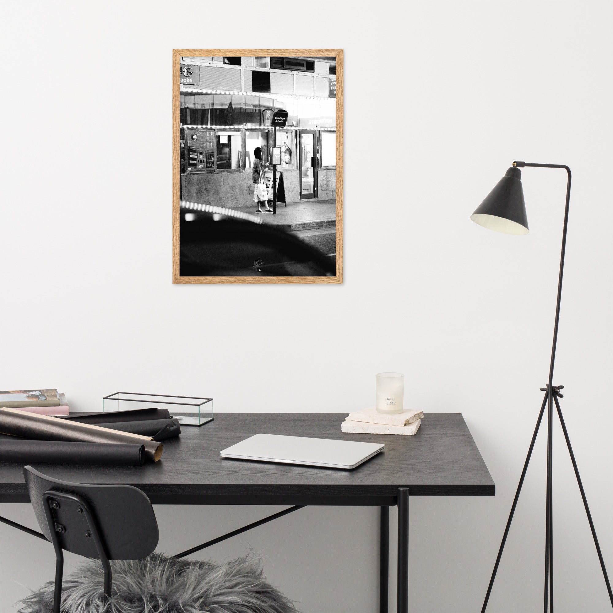 Photographie en noir et blanc d'une femme éclairée par son téléphone dans une rue sombre, mettant en évidence le contraste lumineux de la scène urbaine.