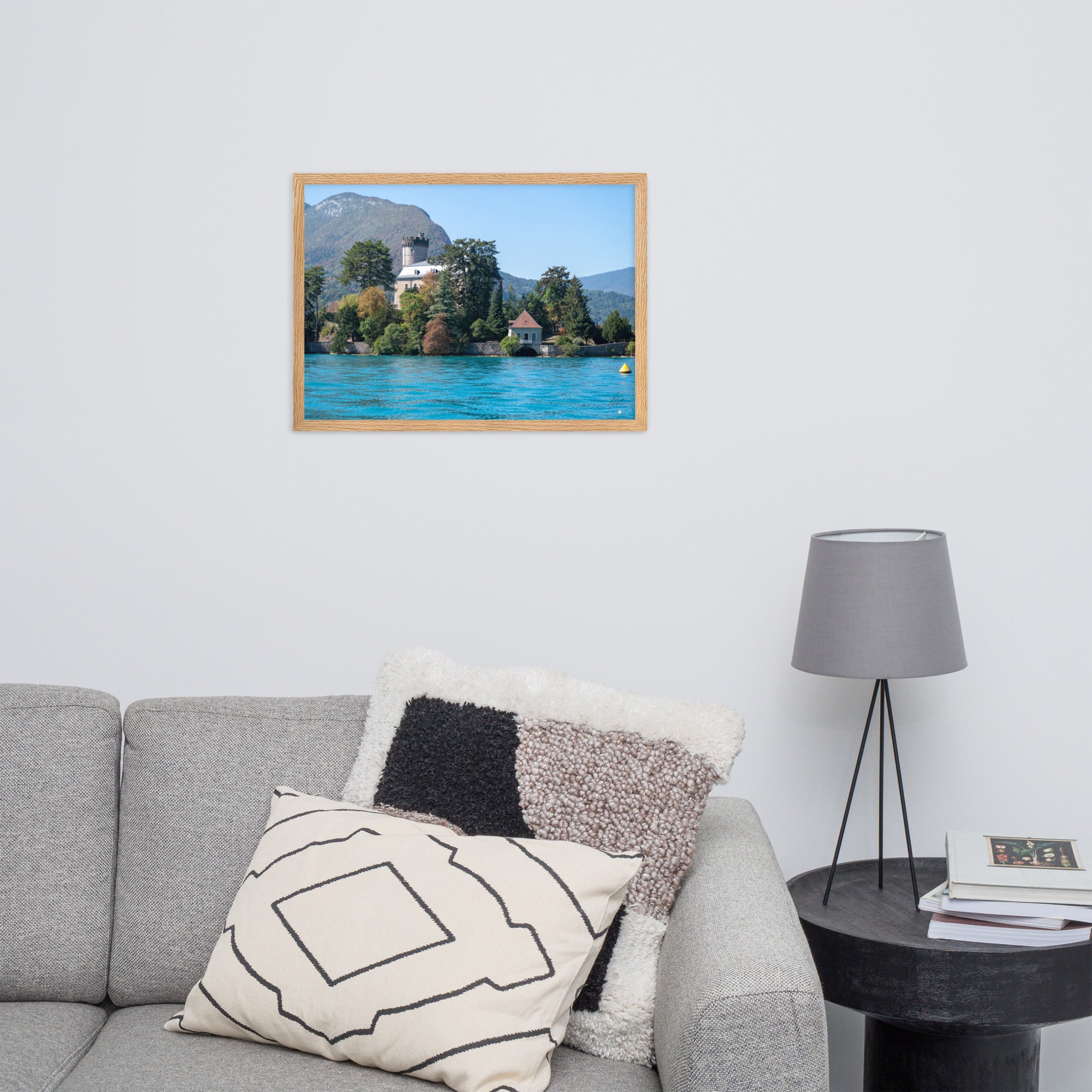 Vue panoramique du Château de Duingt, dominé par des montagnes, avec le Lac d'Annecy reflétant l'édifice, encadré en chêne.