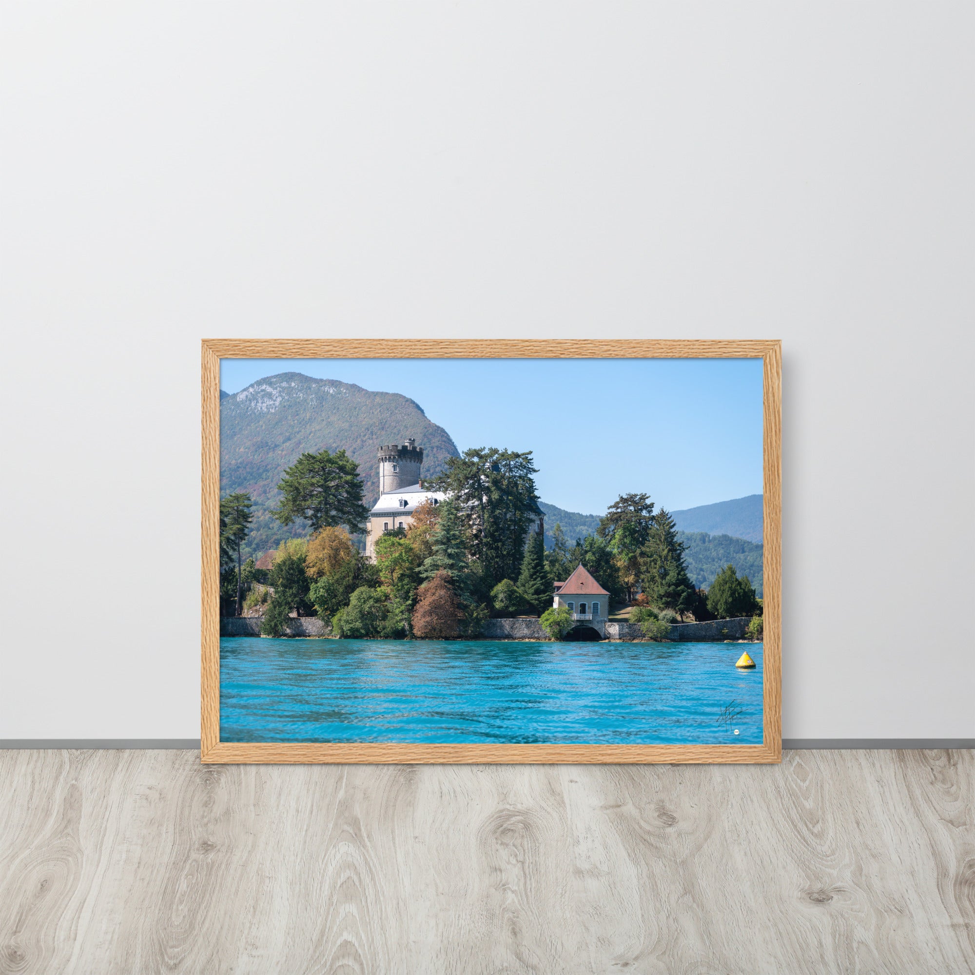 Vue panoramique du Château de Duingt, dominé par des montagnes, avec le Lac d'Annecy reflétant l'édifice, encadré en chêne.