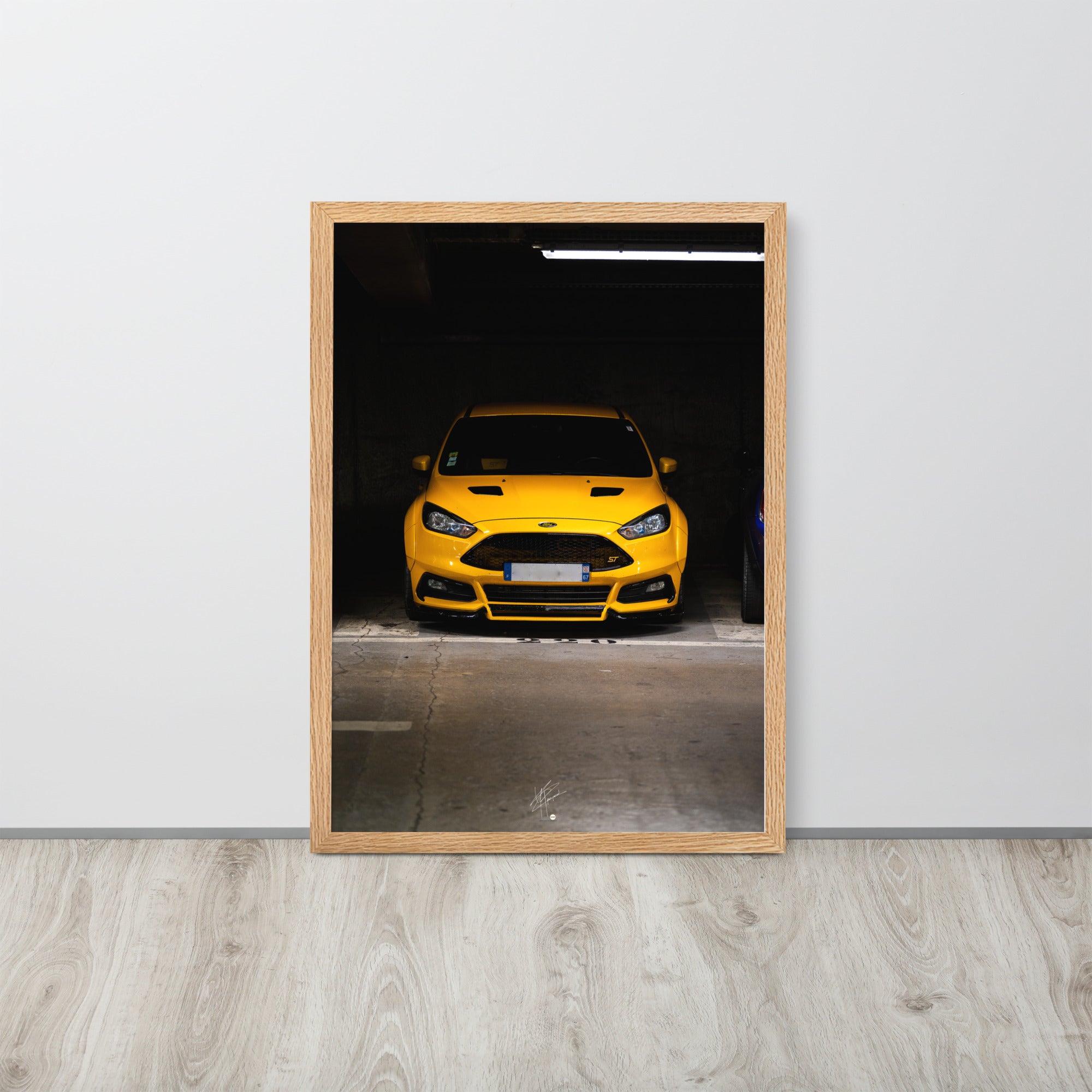 Vue frontale d'une Ford Focus ST en éclatant jaune, mise en lumière dans un parking souterrain avec un éclairage distinctif, encadrement en chêne.