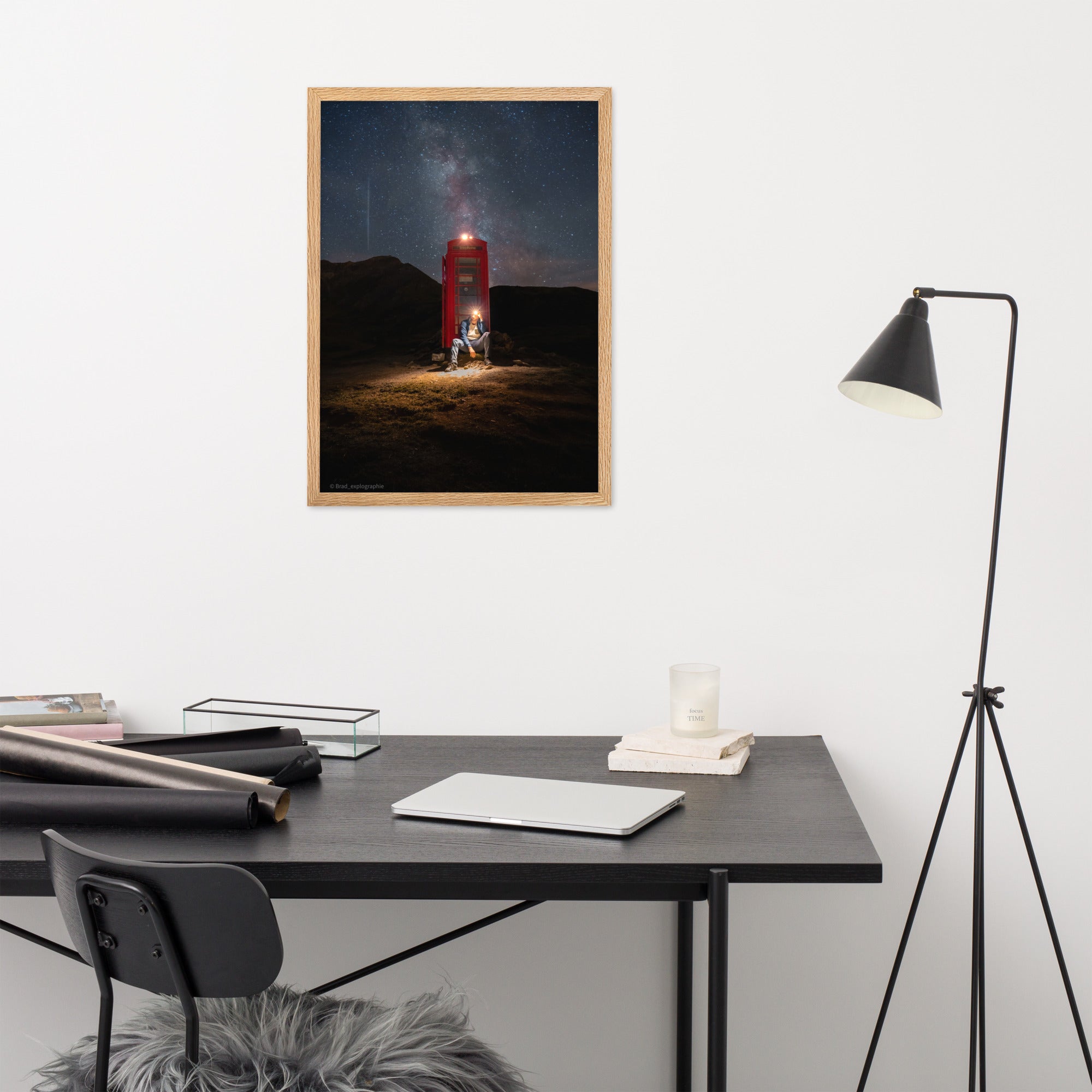 Cabine téléphonique rouge illuminée au milieu de montagnes sombres sous un ciel étoilé par la Voie Lactée, un homme contemple la scène – œuvre signée Brandon Valette.