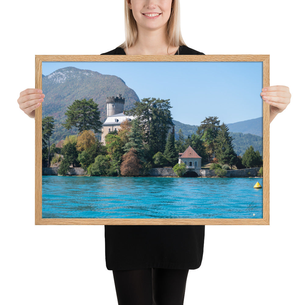 Vue panoramique du Château de Duingt, dominé par des montagnes, avec le Lac d'Annecy reflétant l'édifice, encadré en chêne.