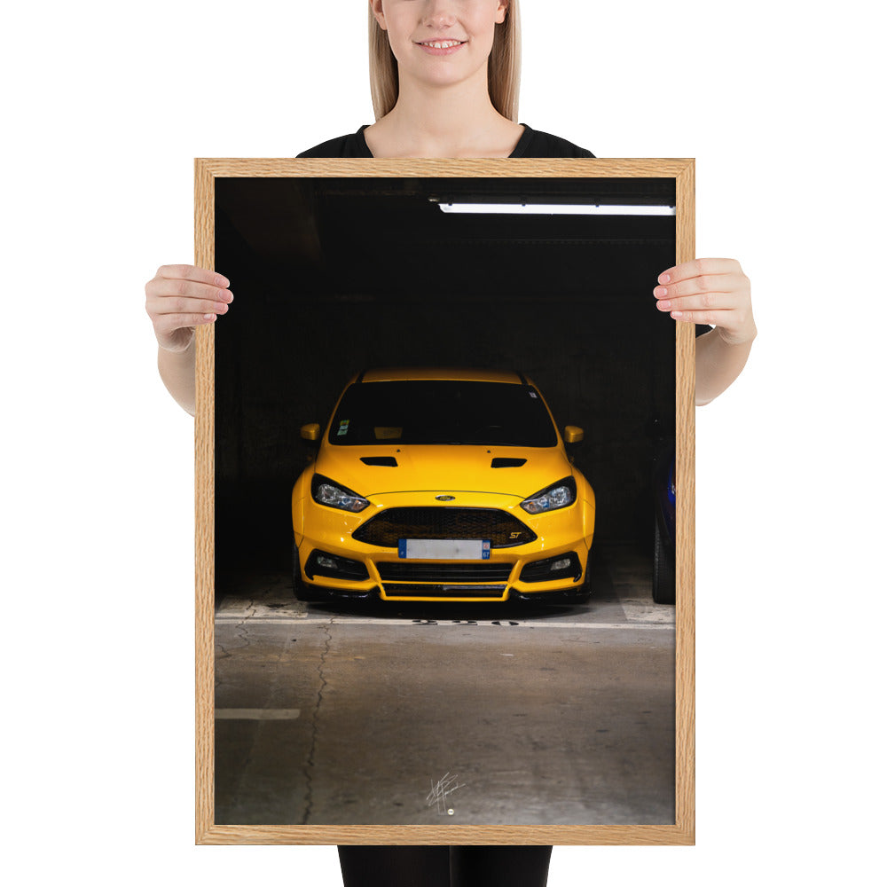 Vue frontale d'une Ford Focus ST en éclatant jaune, mise en lumière dans un parking souterrain avec un éclairage distinctif, encadrement en chêne.