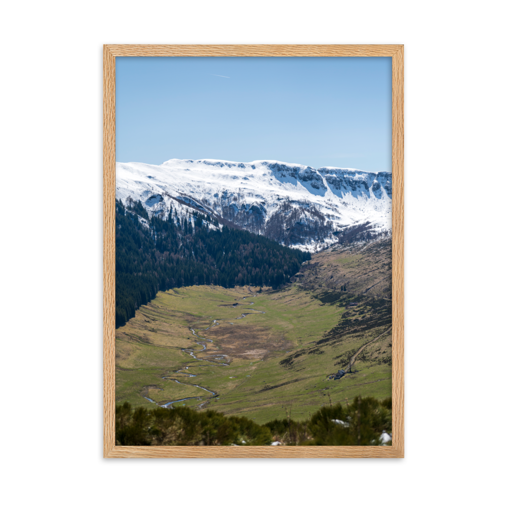 Poster d'une vallée verdoyante avec des montagnes enneigées en arrière-plan, situées dans le Cantal