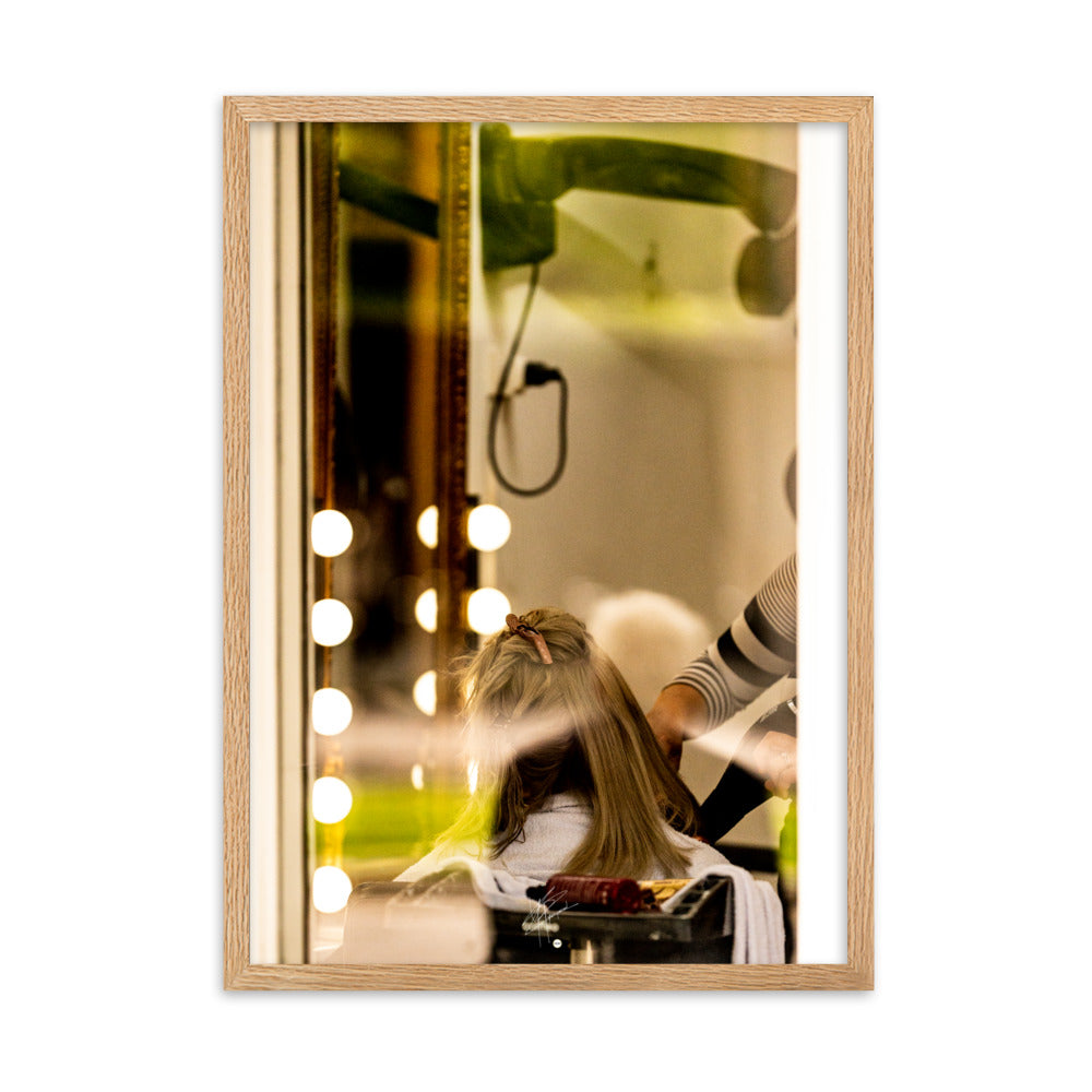 Photographie d'une scène à travers la vitre d'un salon de coiffure, révélant un moment ordinaire mais expressif d'une coiffeuse en plein travail.