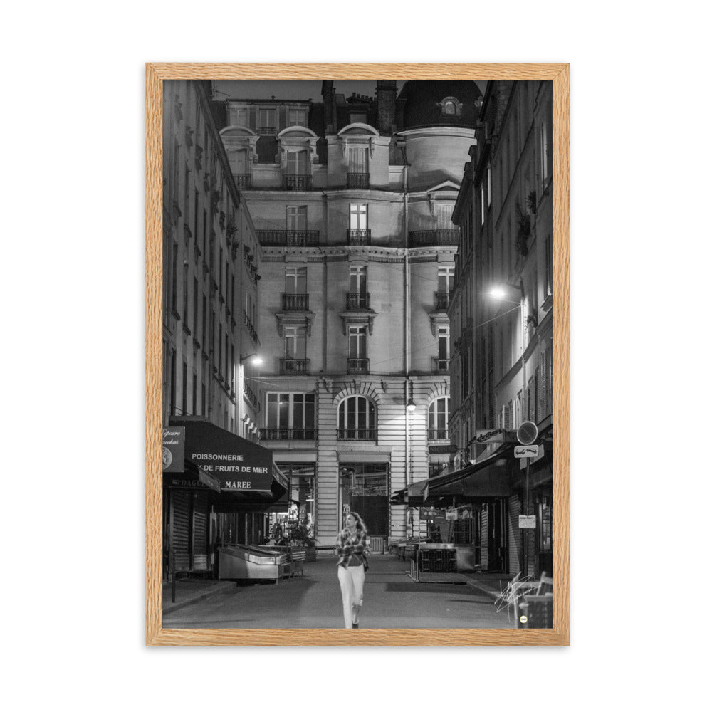 Photographie en noir et blanc d'une rue parisienne déserte la nuit, illuminée par les lumières douces des lampadaires, évoquant une atmosphère mystérieuse et mélancolique.