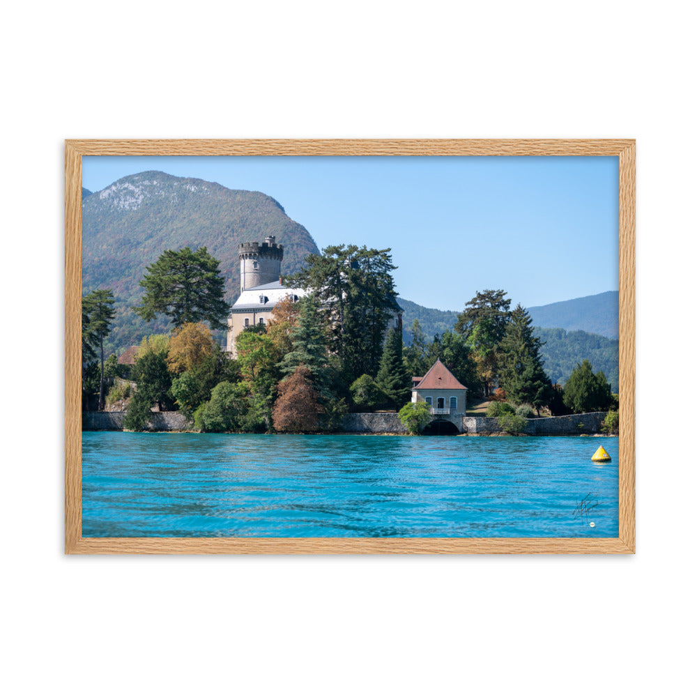 Vue panoramique du Château de Duingt, dominé par des montagnes, avec le Lac d'Annecy reflétant l'édifice, encadré en chêne.