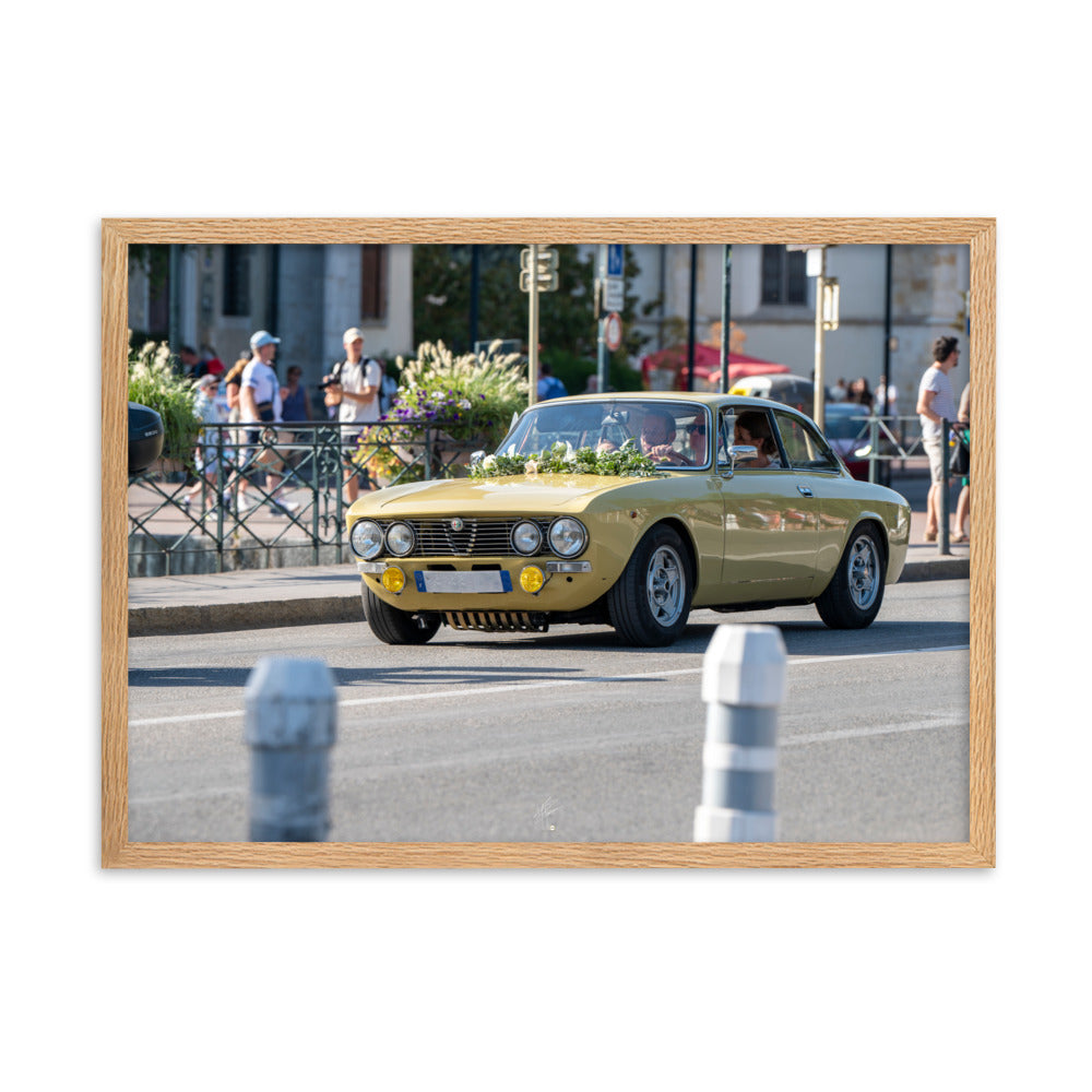 Photographie en angle de la voiture Alpha Romeo GTV, mise en valeur par sa teinte jaune vibrante et sa forme emblématique, stationnée élégamment dans une rue de ville.