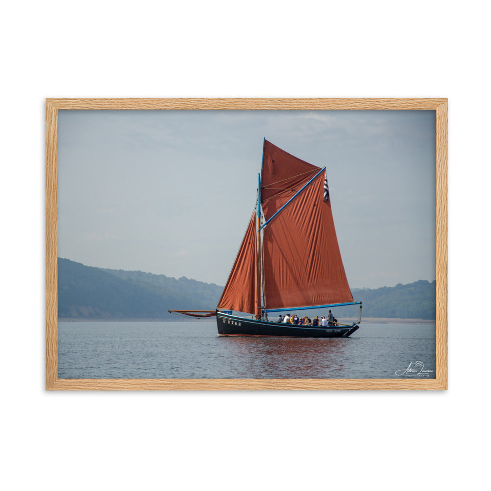 Affiche 'Le cap sur Brest', une image maritime pittoresque par Adrien Louraco, montrant un bateau à voile rouge naviguant à travers le port de Brest, combinant beauté naturelle et charme culturel breton dans une œuvre d'art mural inspirante.