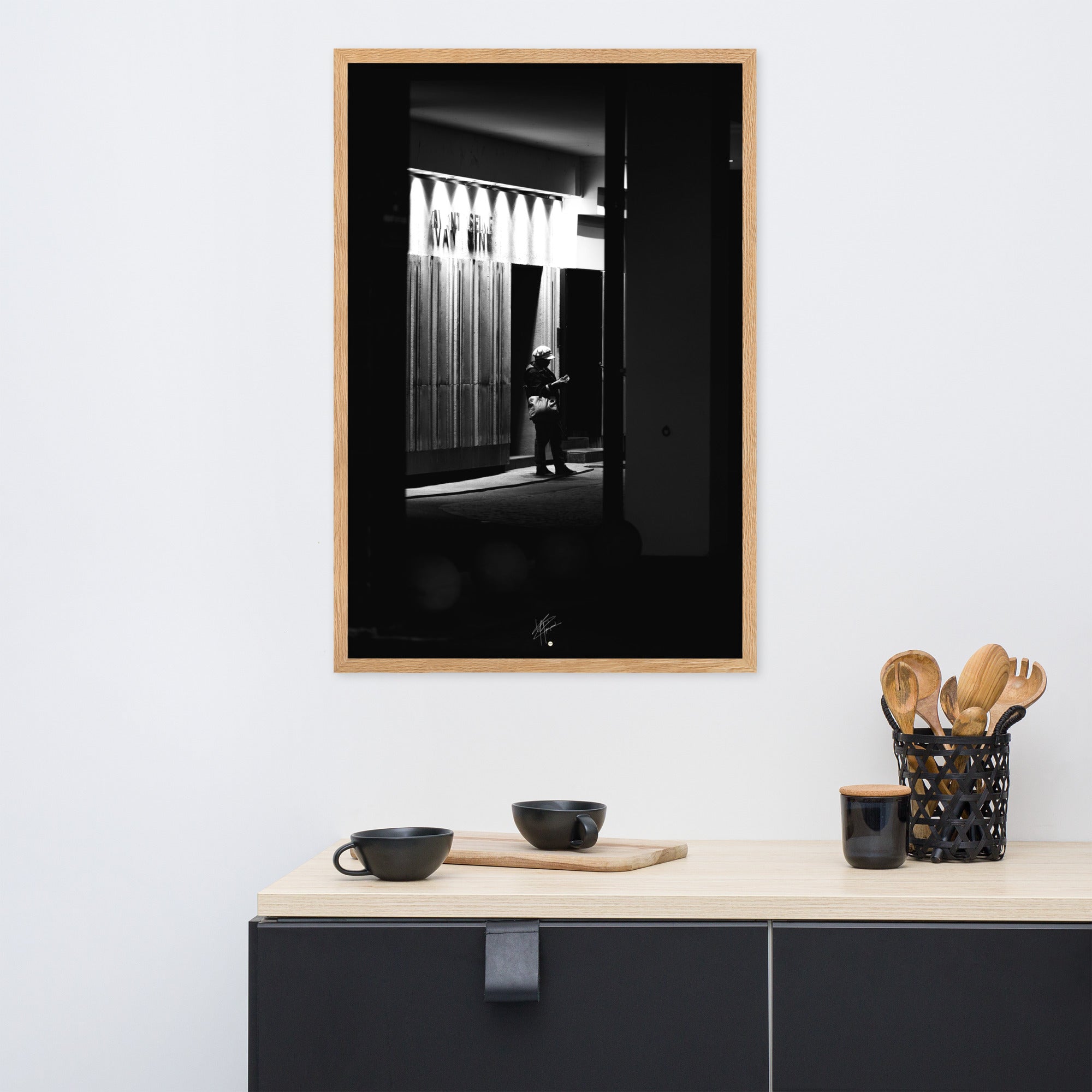 Photographie en noir et blanc d'une femme éclairée par son téléphone dans une rue sombre, mettant en évidence le contraste lumineux de la scène urbaine.