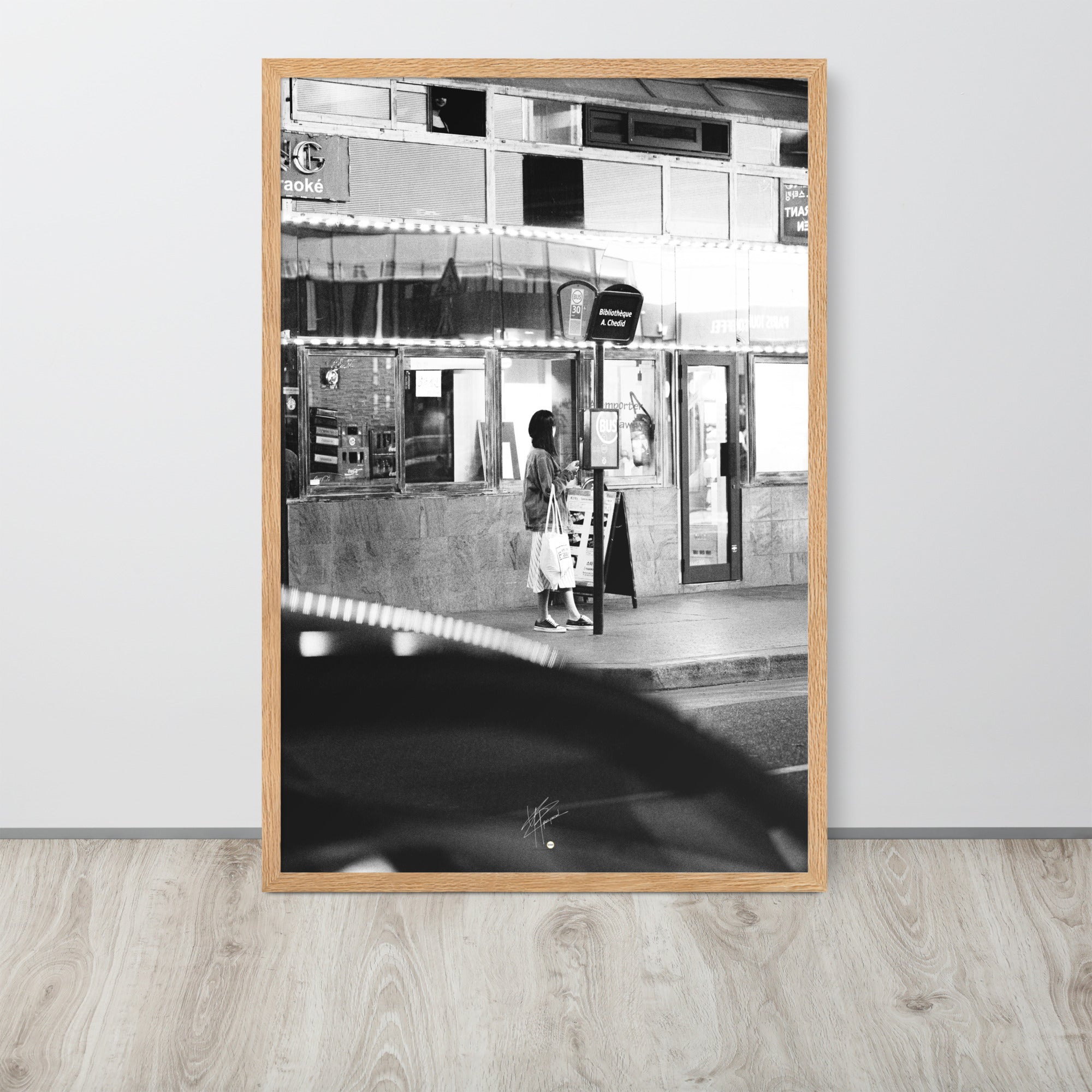 Photographie en noir et blanc d'une femme éclairée par son téléphone dans une rue sombre, mettant en évidence le contraste lumineux de la scène urbaine.