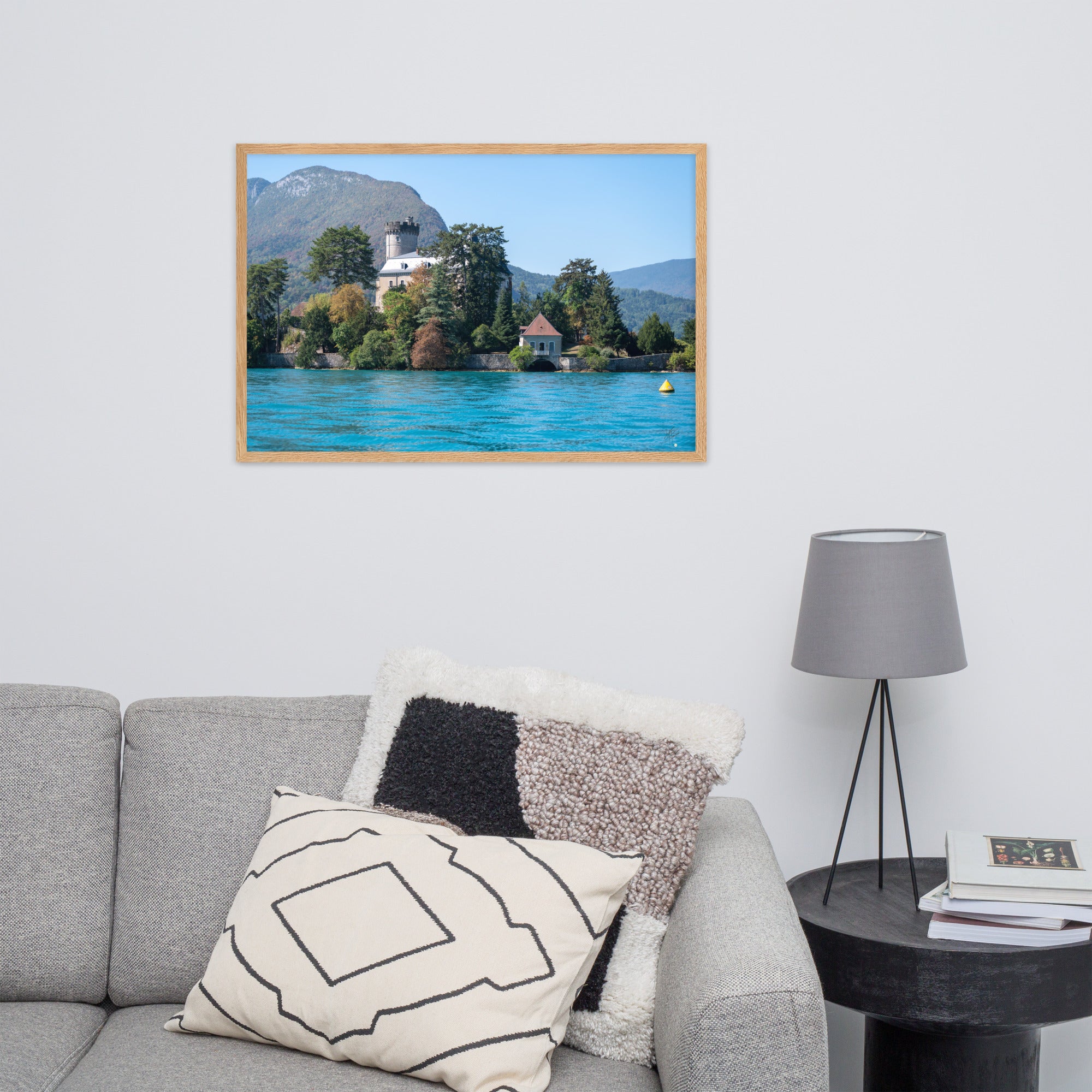 Vue panoramique du Château de Duingt, dominé par des montagnes, avec le Lac d'Annecy reflétant l'édifice, encadré en chêne.