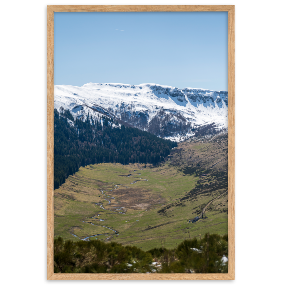 Poster d'une vallée verdoyante avec des montagnes enneigées en arrière-plan, situées dans le Cantal