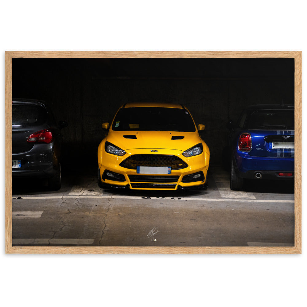 Ford Focus ST jaune brillamment éclairée dans un parking souterrain sombre, encadrement en bois de chêne massif.