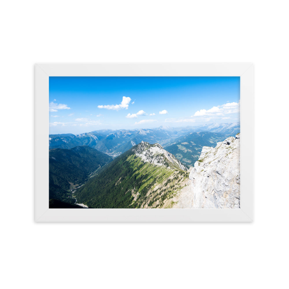 Photographie panoramique des Alpes avec montagnes robustes, vallées verdoyantes, nuages flottants et ciel bleu azur.