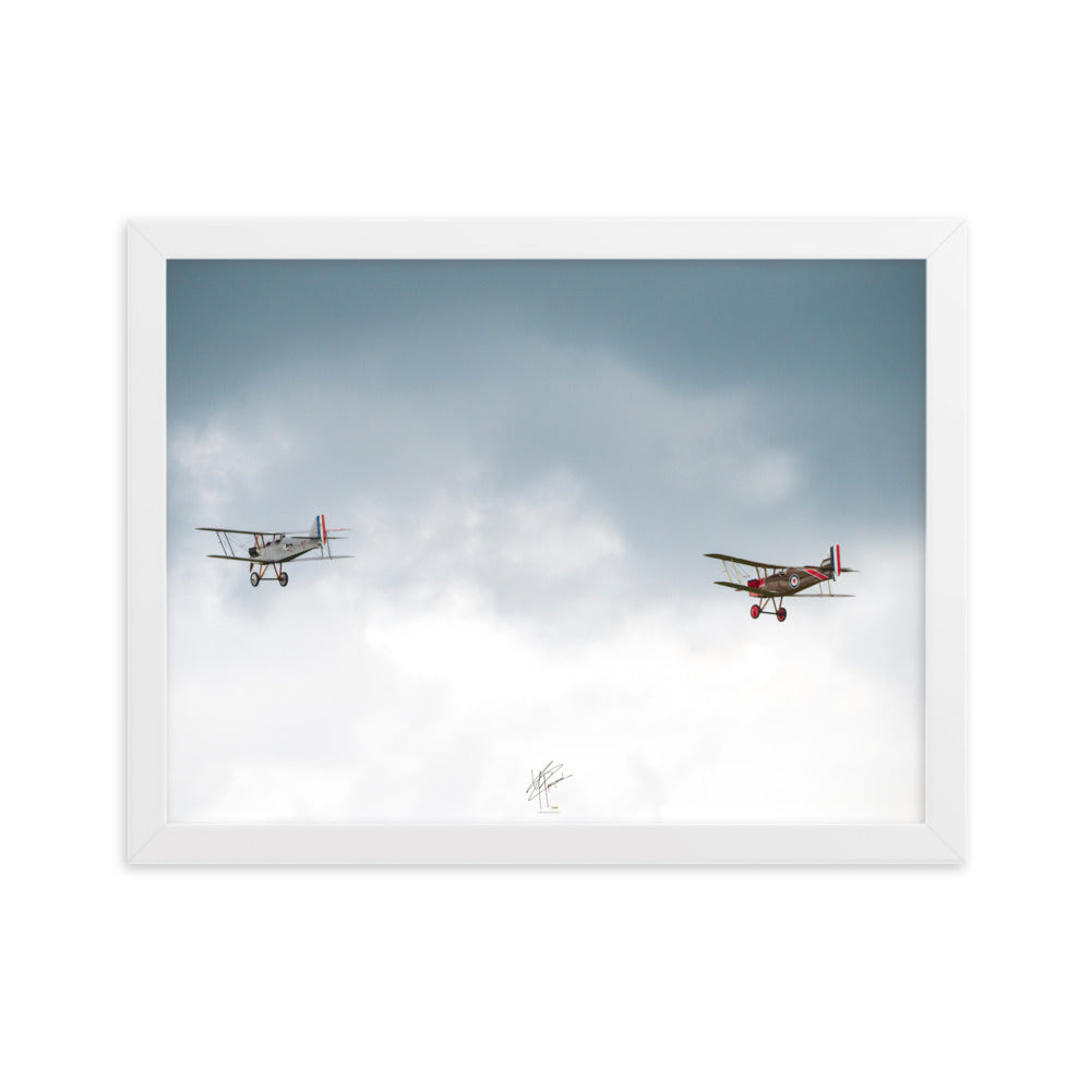 Deux avions de combat de la Première Guerre Mondiale s'élevant contre un ciel gris-blanc, encapsulant l'héroïsme de l'époque. Poster encadré de haute qualité signé 'Tagazou'.