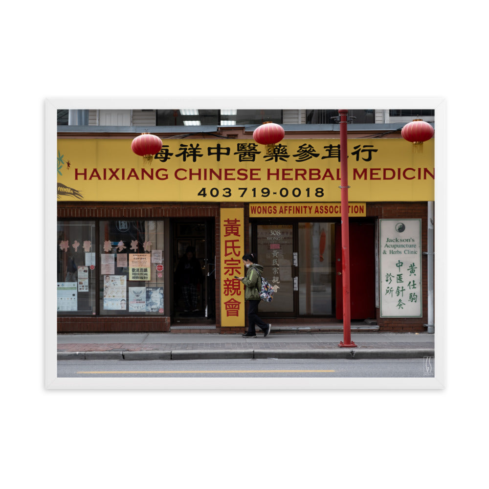 Photographie de rue à Calgary montrant une femme avec un masque abaissé devant une boutique d'herbes médicinales chinoises, capturée par Galdric Sibiude, reflétant le quotidien urbain.