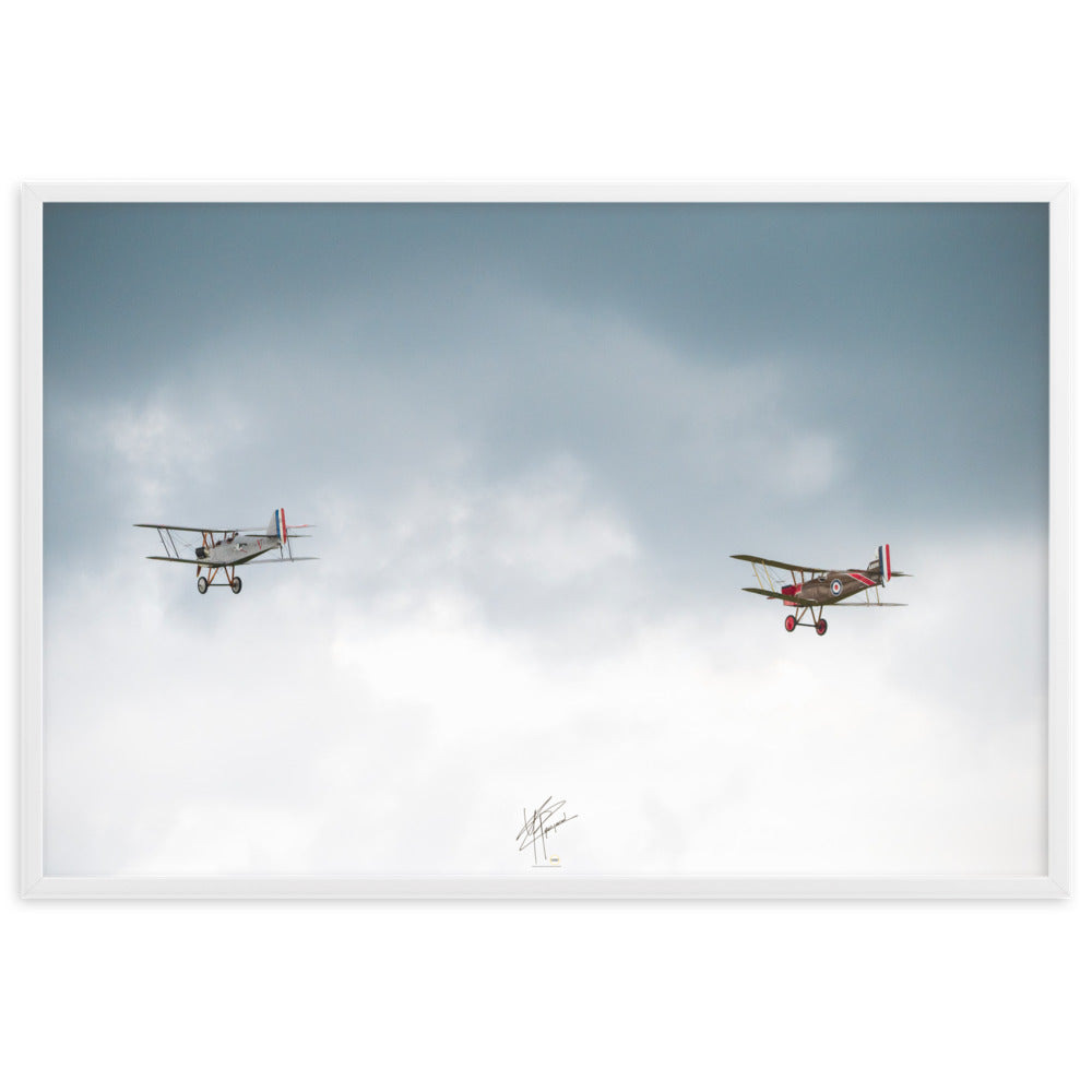 Deux avions de combat de la Première Guerre Mondiale s'élevant contre un ciel gris-blanc, encapsulant l'héroïsme de l'époque. Poster encadré de haute qualité signé 'Tagazou'.