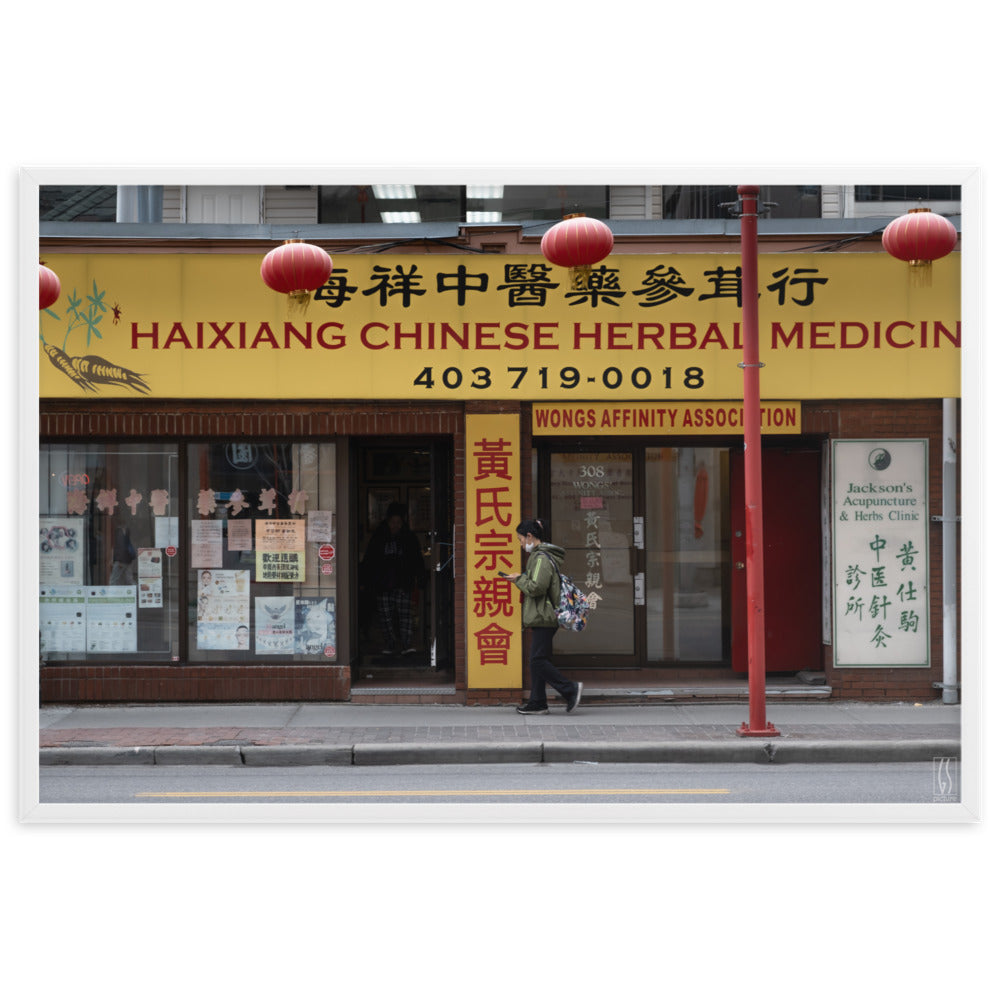 Photographie de rue à Calgary montrant une femme avec un masque abaissé devant une boutique d'herbes médicinales chinoises, capturée par Galdric Sibiude, reflétant le quotidien urbain.