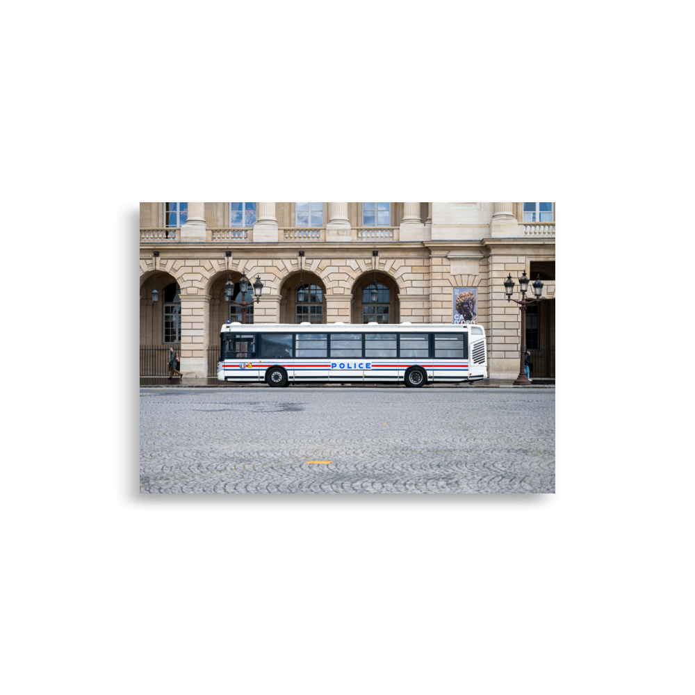 Photographie d'un bus de la police stationné sur une rue pavée à Paris, avec un bâtiment historique en arrière-plan.