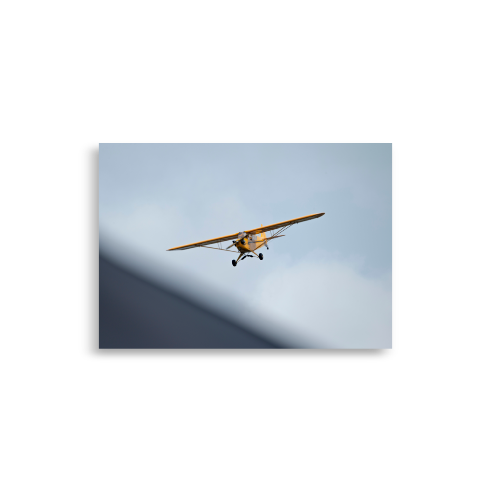 Photographie d'un Piper Cub jaune en plein vol.