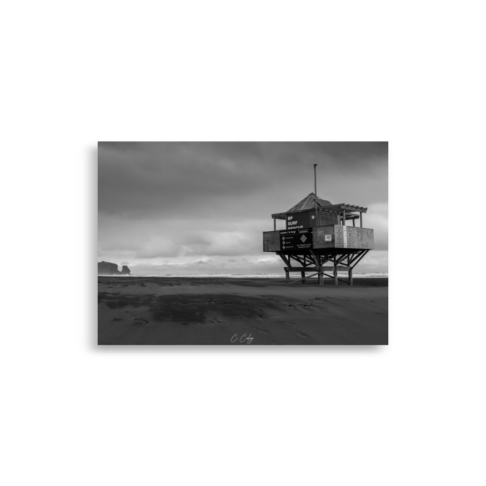 Photographie monochrome de l'emblématique abri sur pilotis des sauveteurs, dominant une plage néo-zélandaise, capturée par Charles Coley.