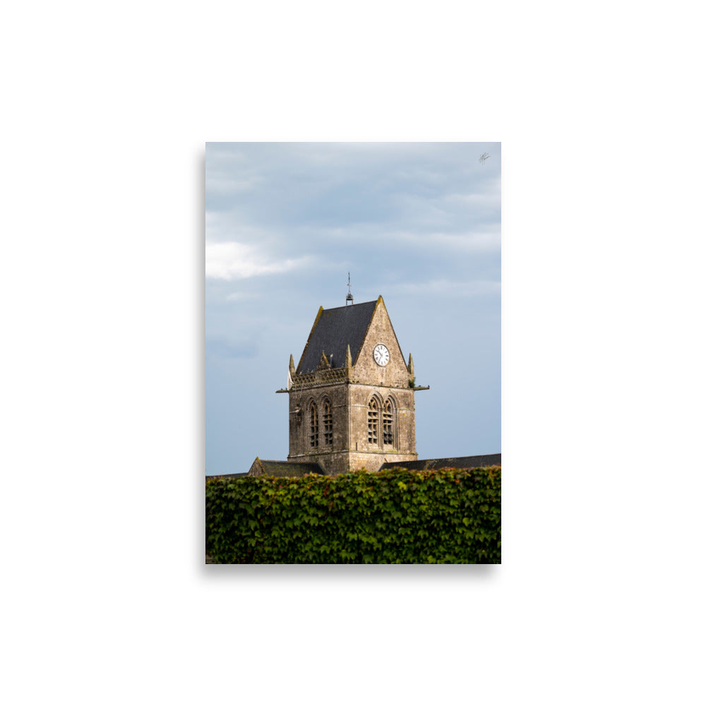 Vue pittoresque de l'église historique Sainte-Mère-Église sous un ciel nuageux, capturée dans un poster haut de gamme.