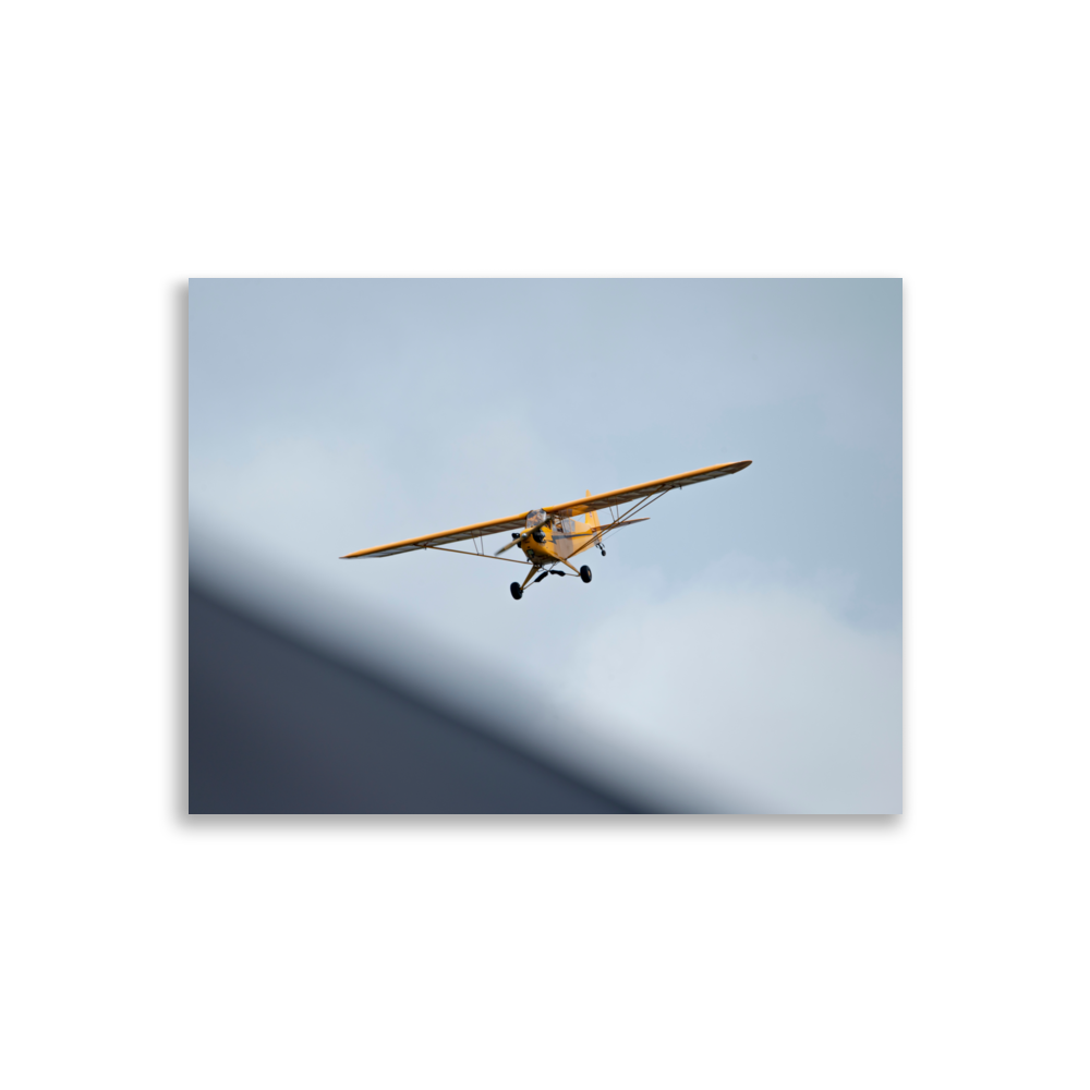 Photographie d'un Piper Cub jaune en plein vol.