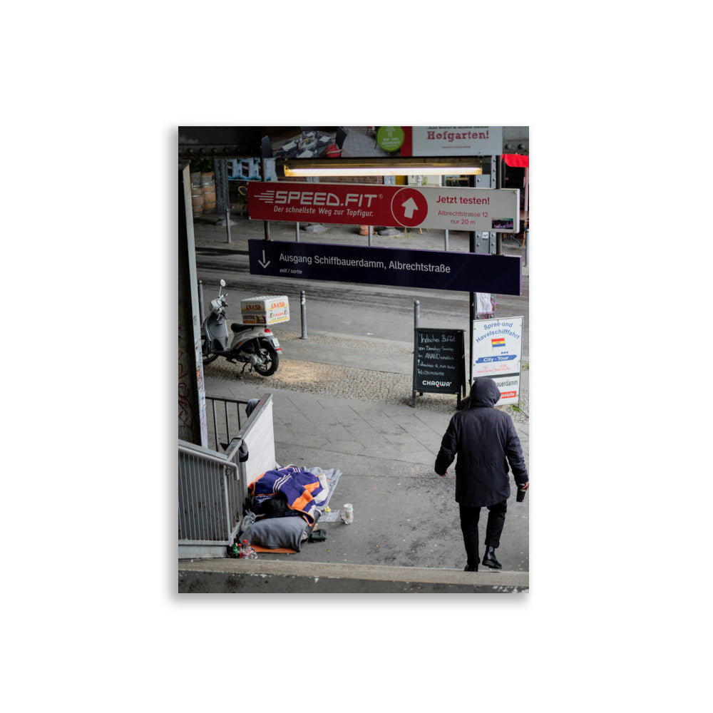 Photographie 'Contrastes de Berlin' montrant un homme sans domicile fixe reposant sous le métro berlinois, juxtaposé à un scooter de livraison alimentaire