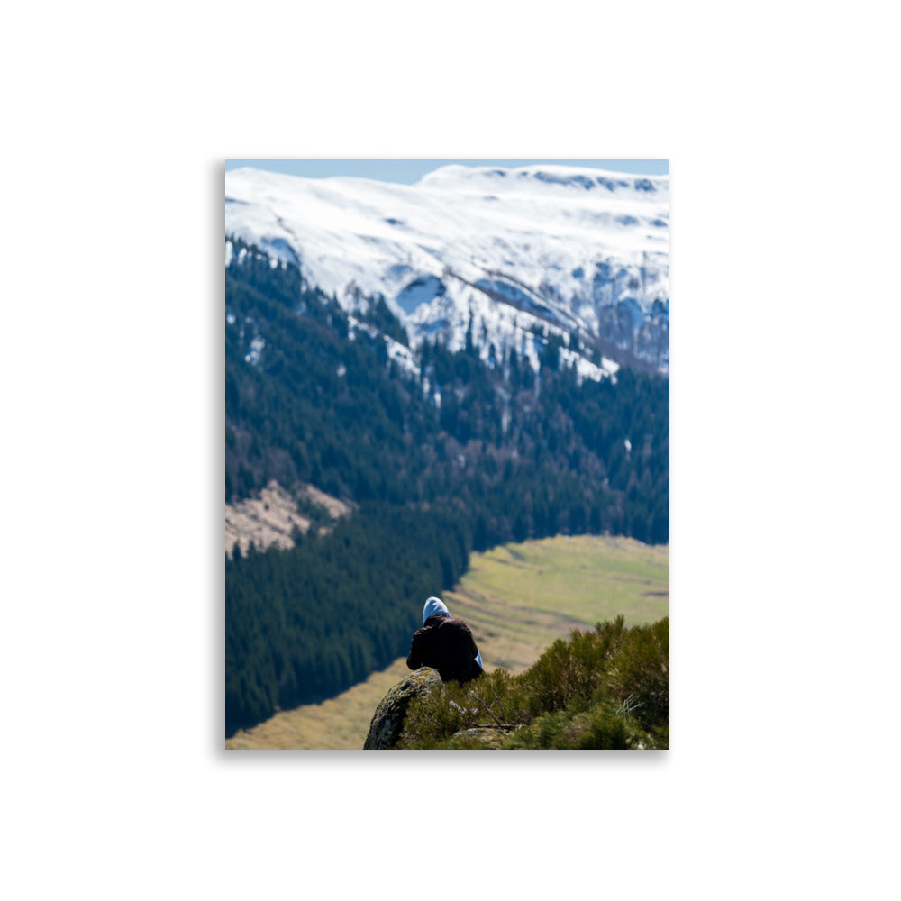 Figure en méditation sur une montagne du Cantal, vaste paysage en arrière-plan.