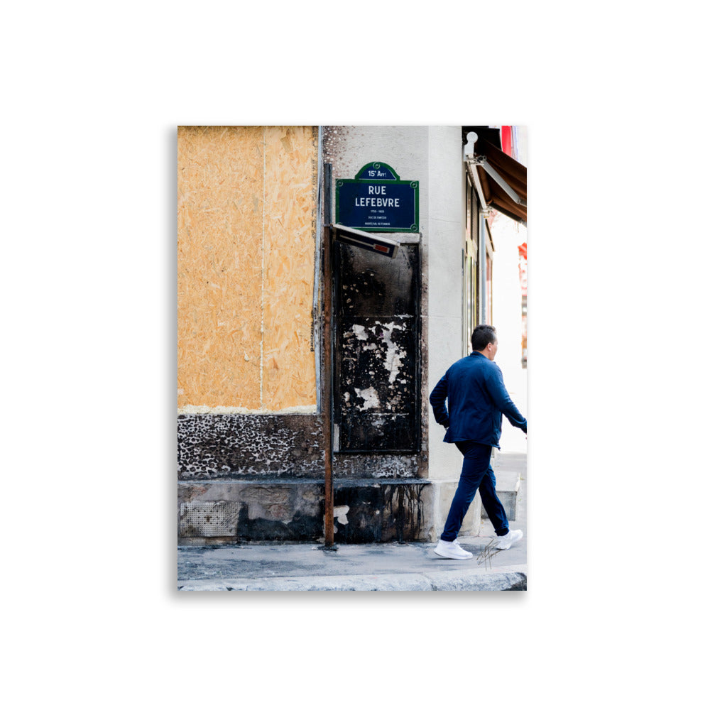 Photographie de la "Rue Lefebvre" après un incendie, montrant des traces de suie, un panneau de sens interdit plié et un passant.