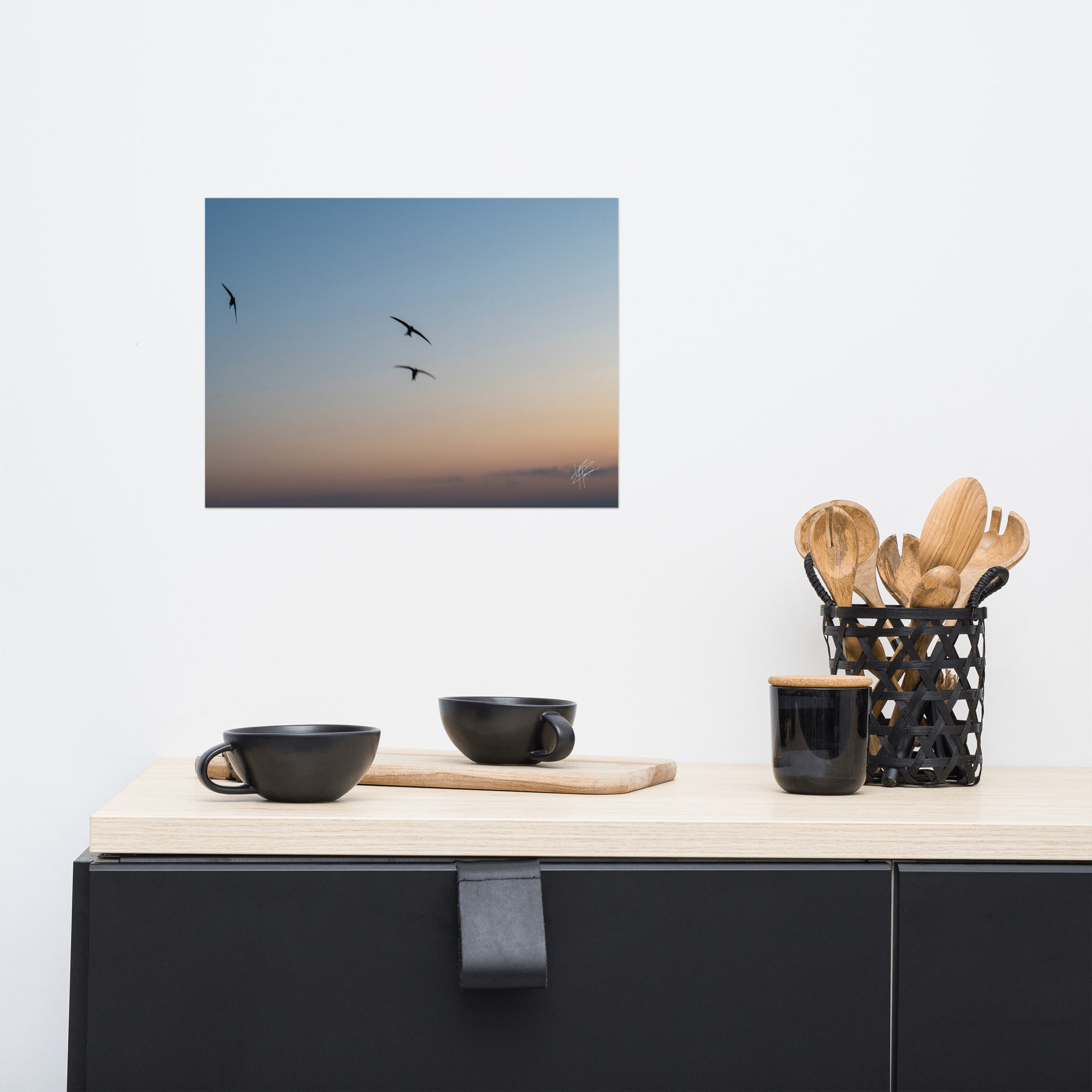 Trois oiseaux volant dans un ciel aux teintes de bleu, orange et jaune.