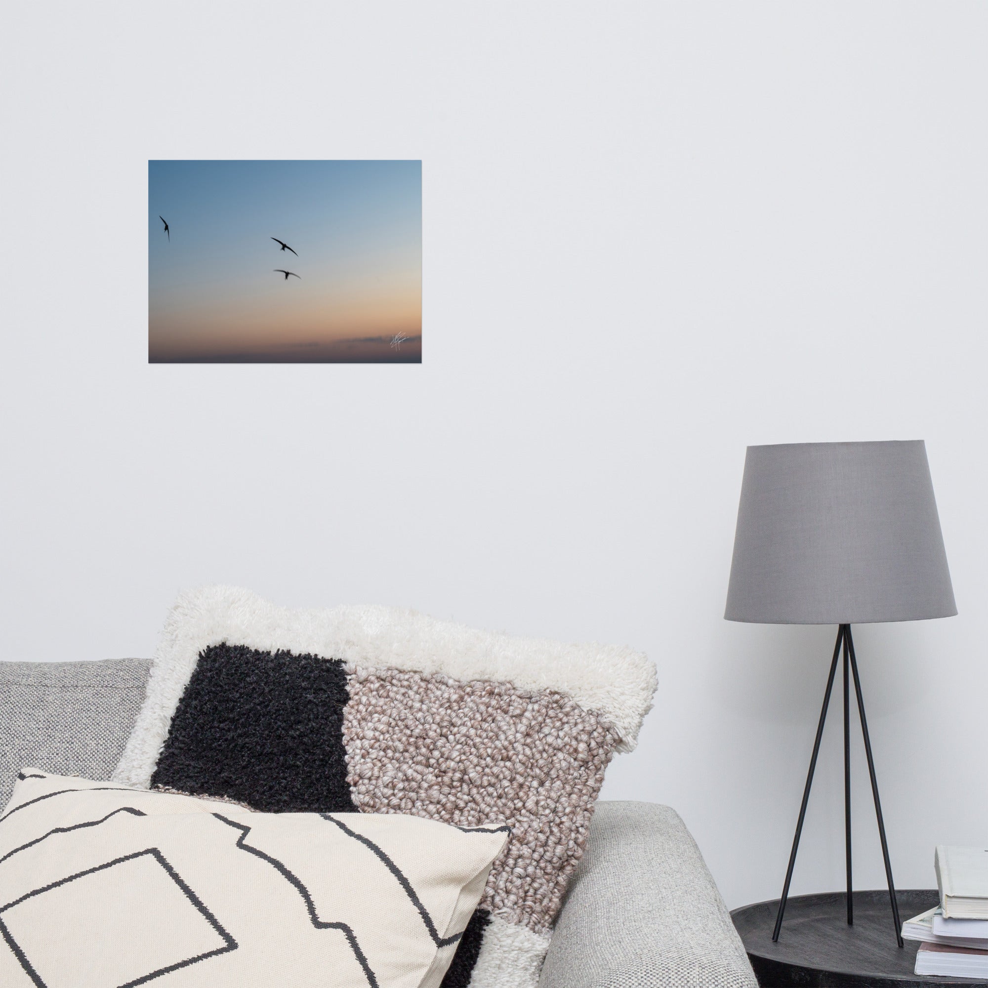 Trois oiseaux volant dans un ciel aux teintes de bleu, orange et jaune.