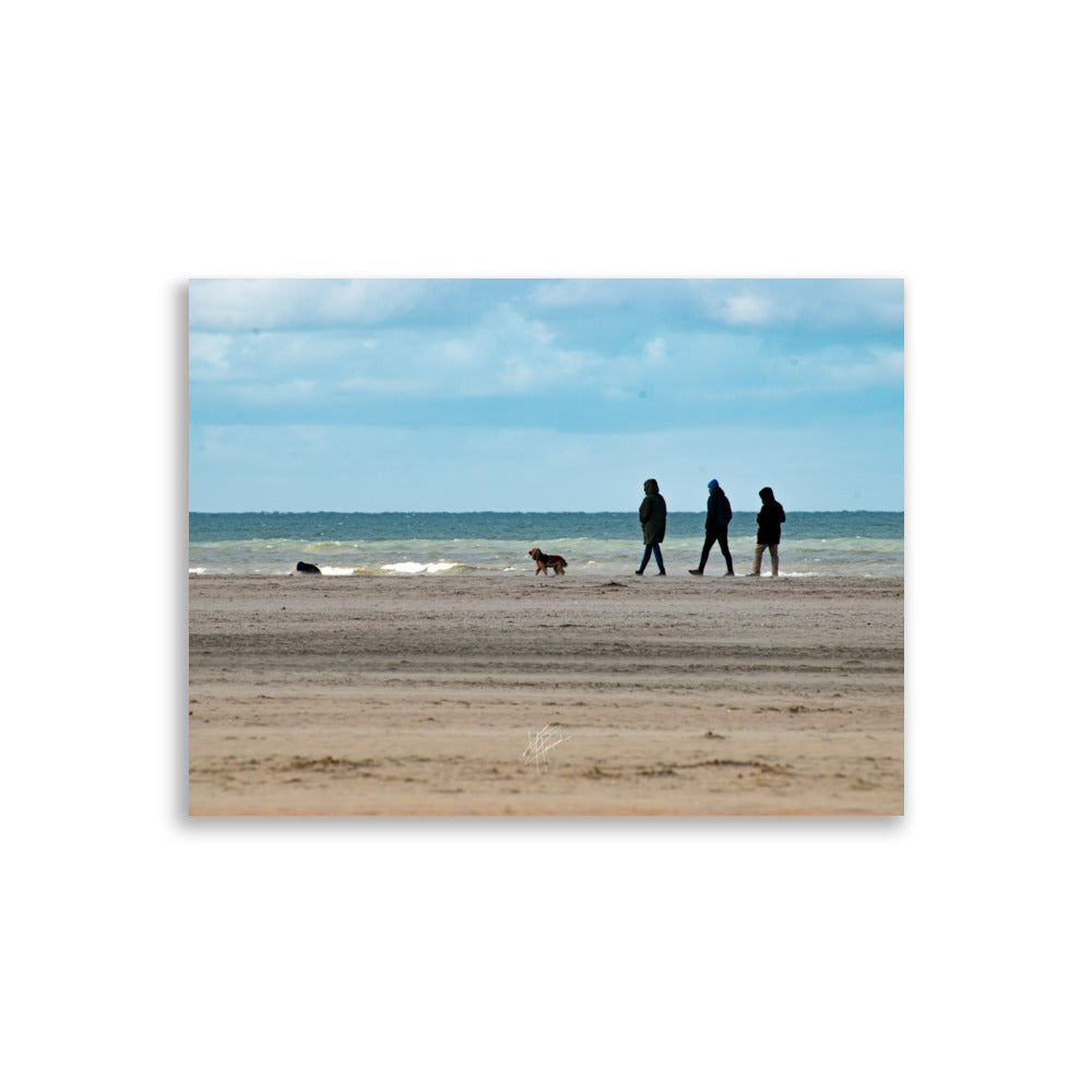 Photographie de la plage de Deauville avec des promeneurs et leur chien, capturant l'atmosphère tranquille et l'immensité de la mer normande.