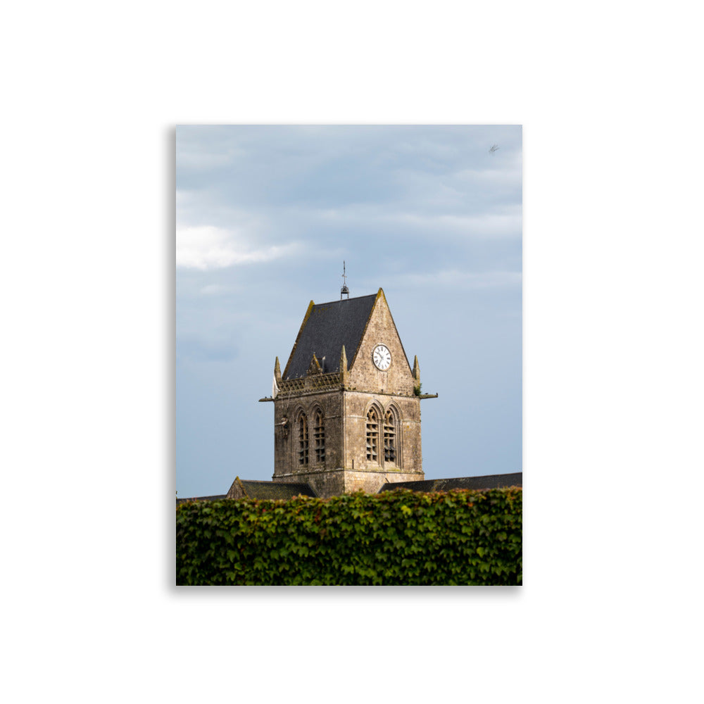 Vue pittoresque de l'église historique Sainte-Mère-Église sous un ciel nuageux, capturée dans un poster haut de gamme.