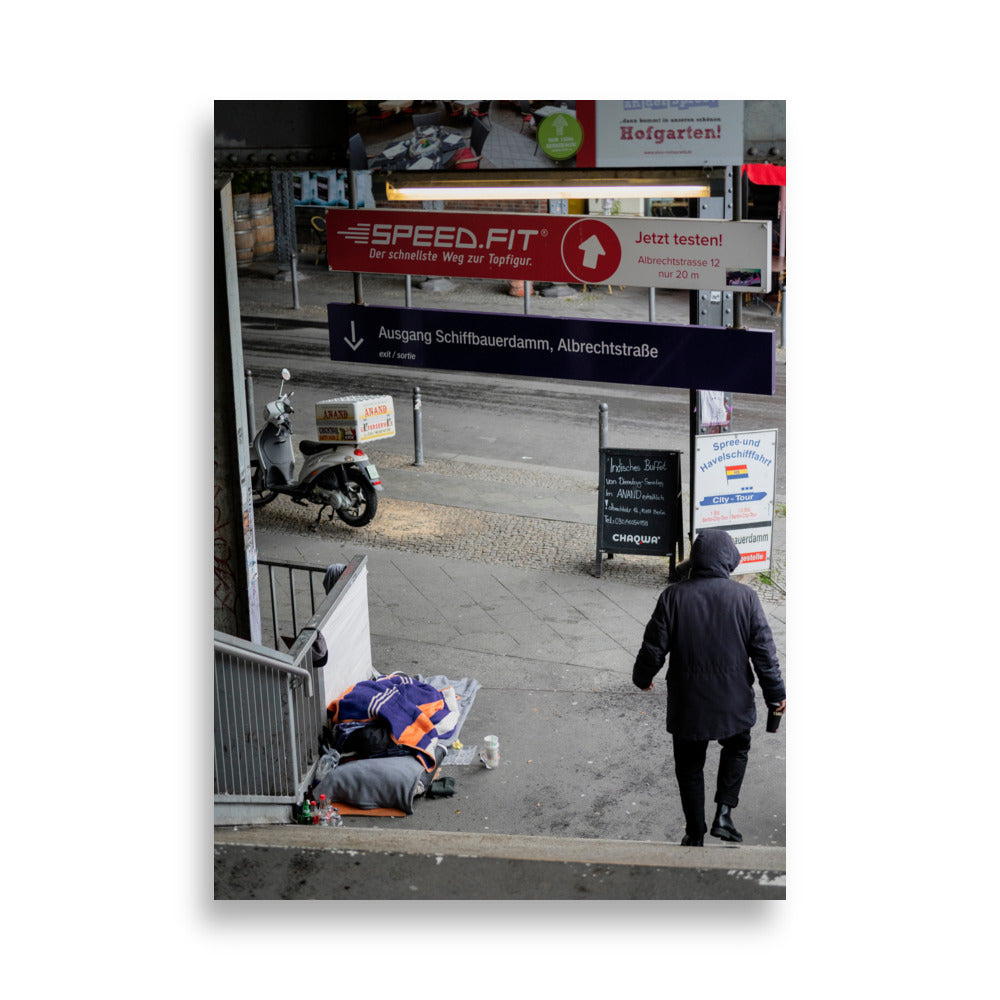 Photographie 'Contrastes de Berlin' montrant un homme sans domicile fixe reposant sous le métro berlinois, juxtaposé à un scooter de livraison alimentaire