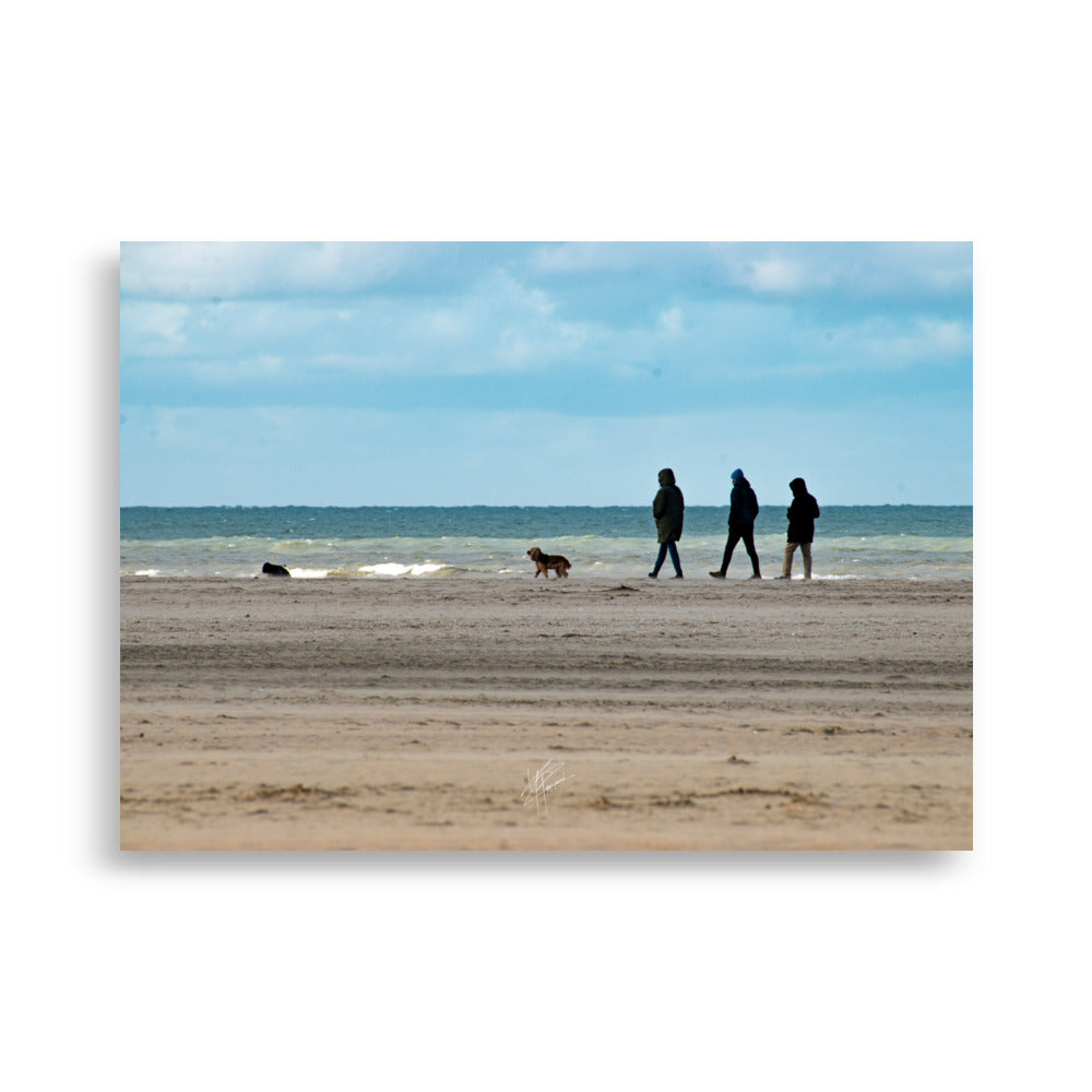 Photographie de la plage de Deauville avec des promeneurs et leur chien, capturant l'atmosphère tranquille et l'immensité de la mer normande.